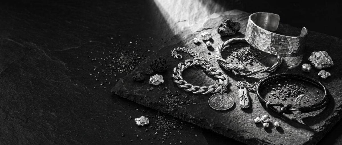 Men's 999 fine silver jewelry arranged on dark stone
