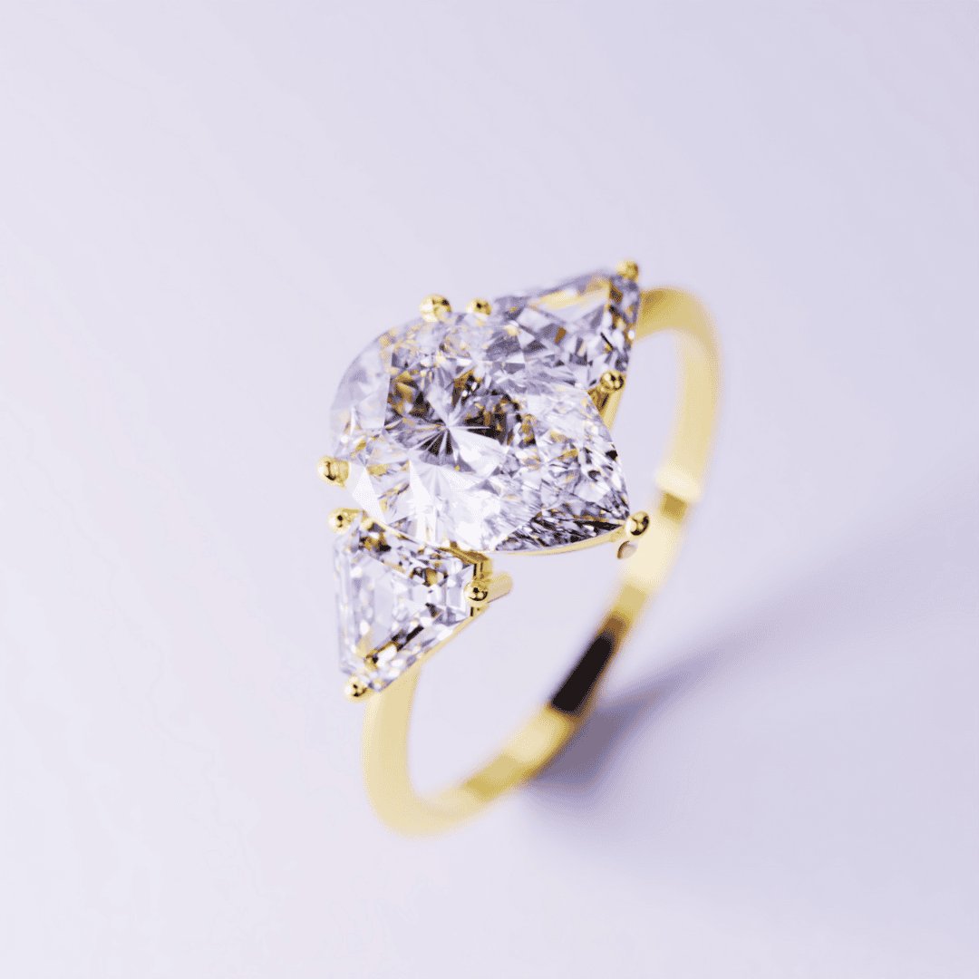 A gold-toned ring featuring a large pear-shaped clear stone flanked by two triangular clear side stones.