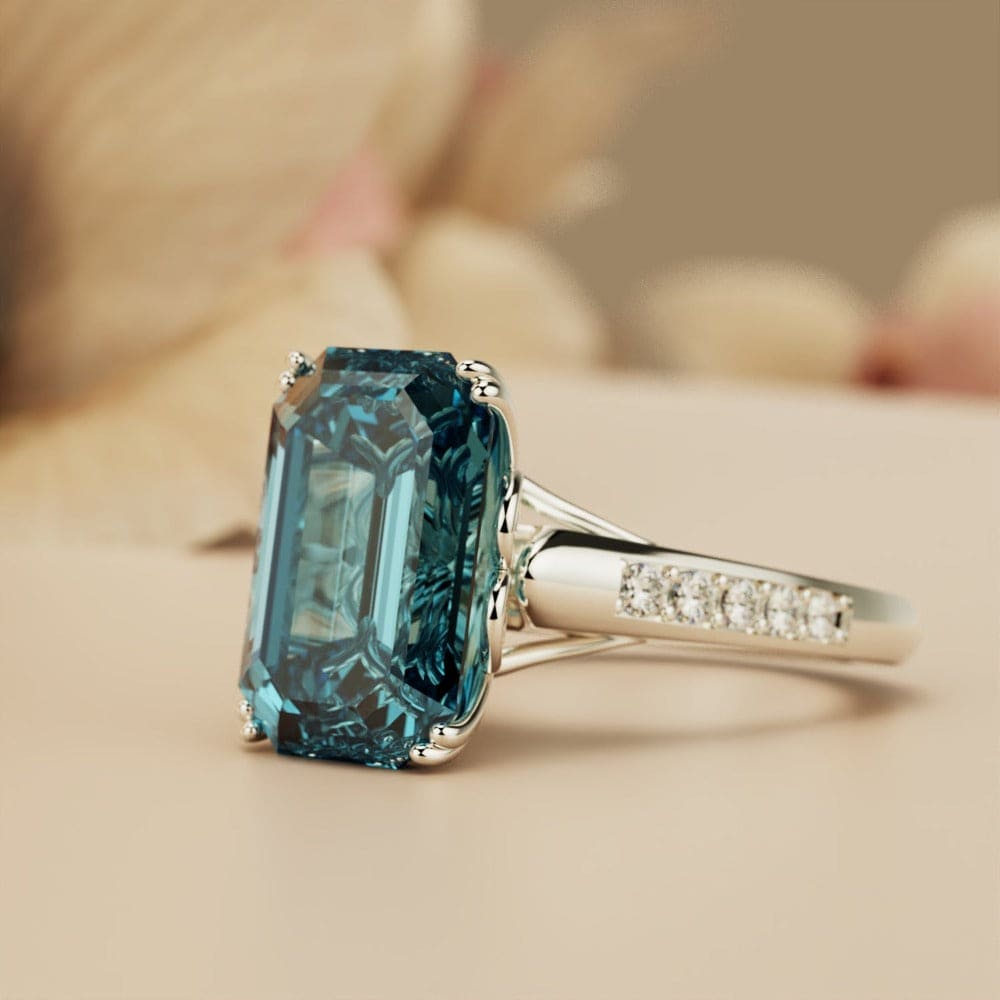 Silver-toned ring with a large rectangular teal gemstone and small clear accent stones along the band.