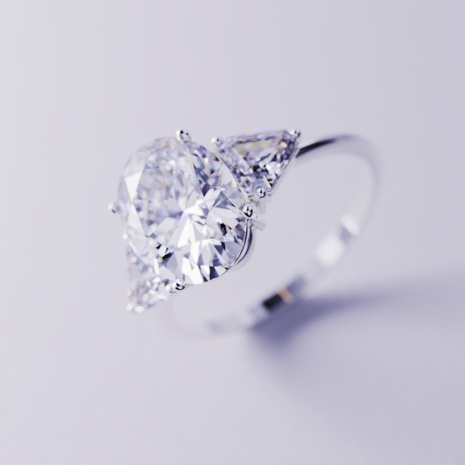 Silver-toned three-stone ring with a large pear-shaped faceted center gem and two triangular side gems.