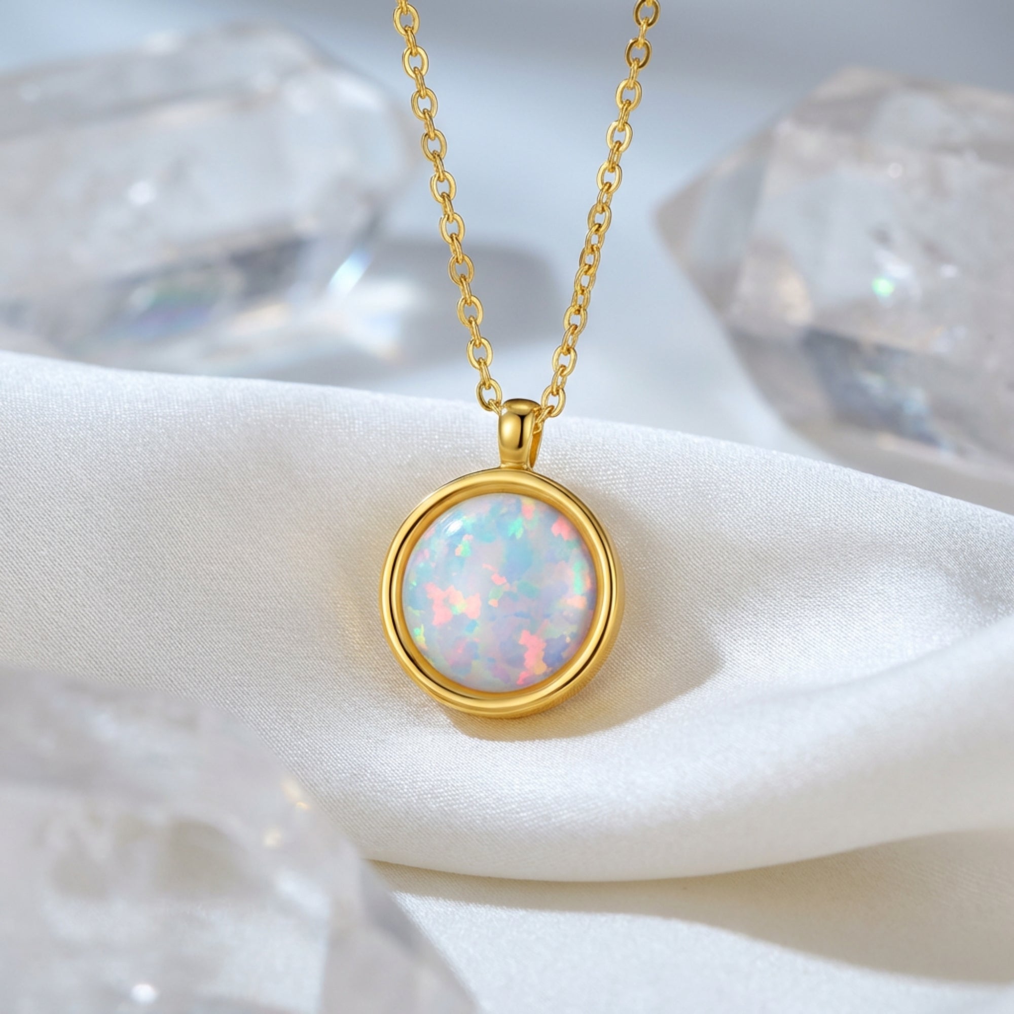 Gold finish round cut white opal necklace resting on white silk fabric with crystal accents.