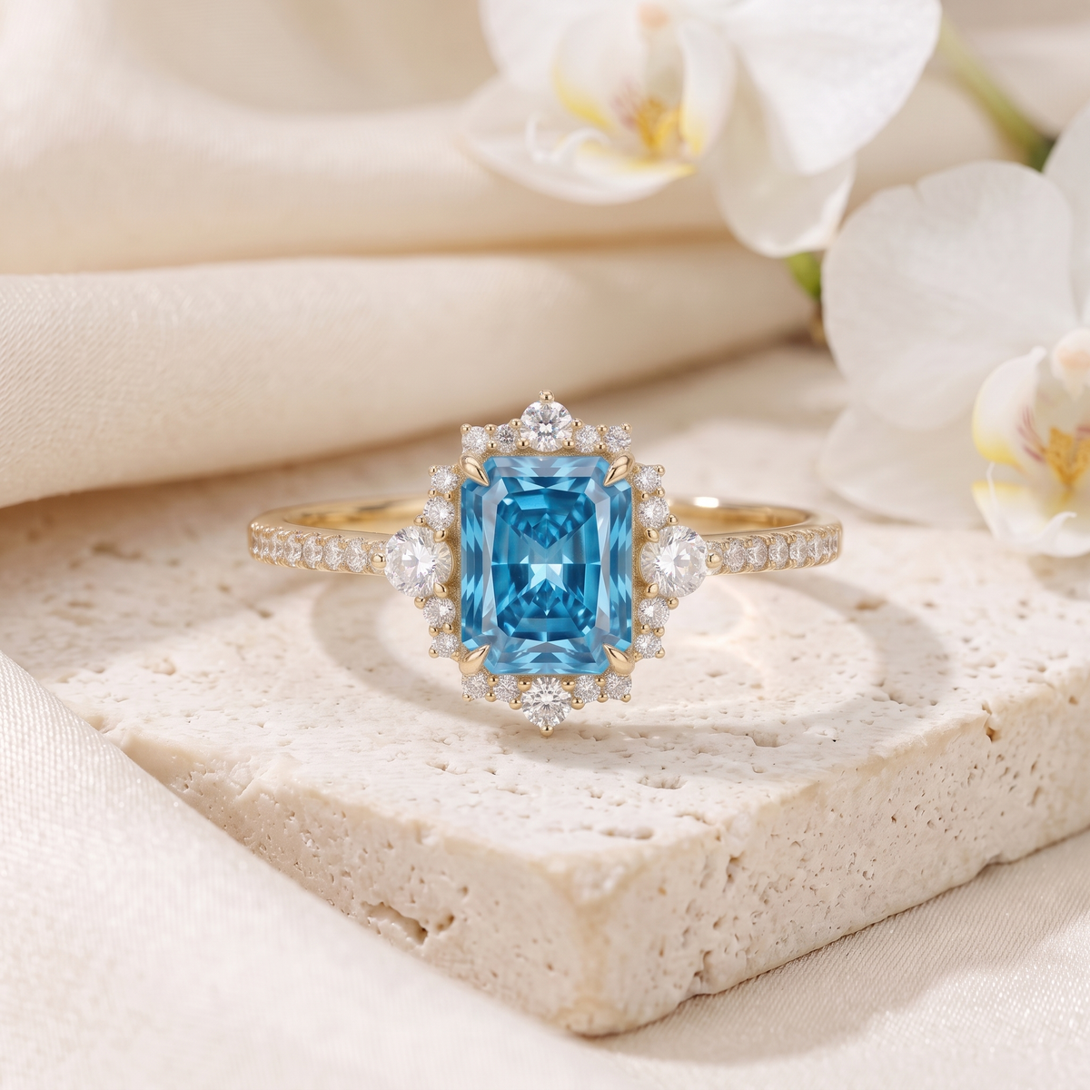 Emerald cut blue moissanite vintage halo engagement ring in yellow gold displayed on stone.