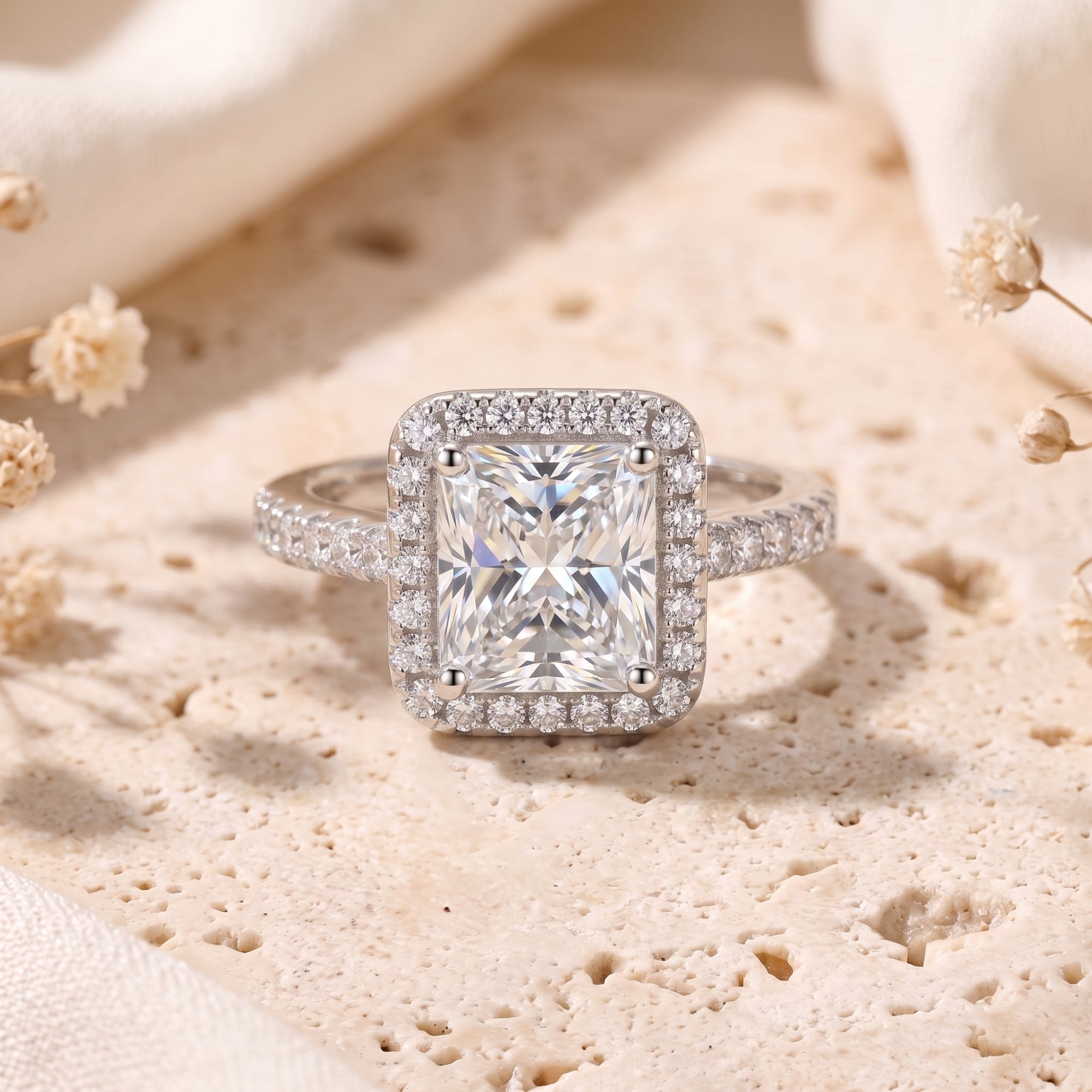 Front view of a radiant-cut cubic zirconia halo promise ring in sterling silver on a stone surface.