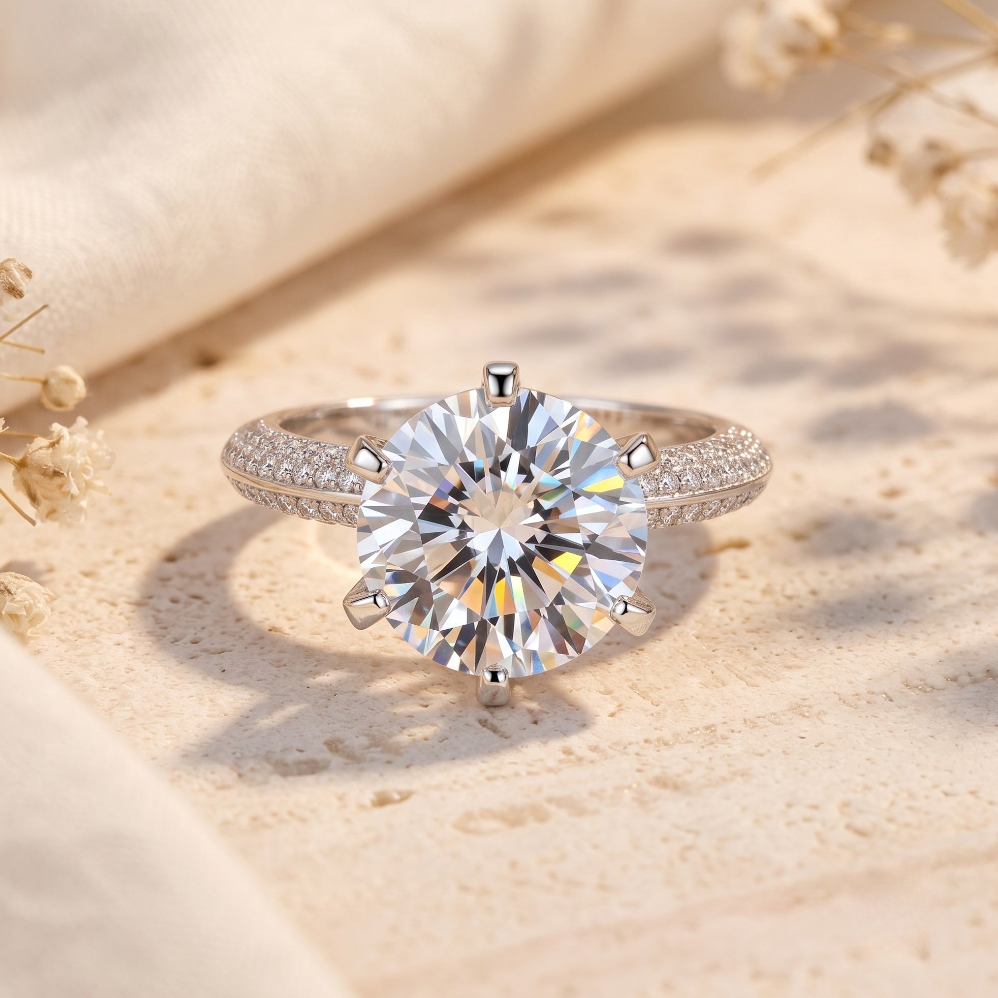 Round-cut CZ solitaire ring in S925 sterling silver with pavé band on a neutral lifestyle background.