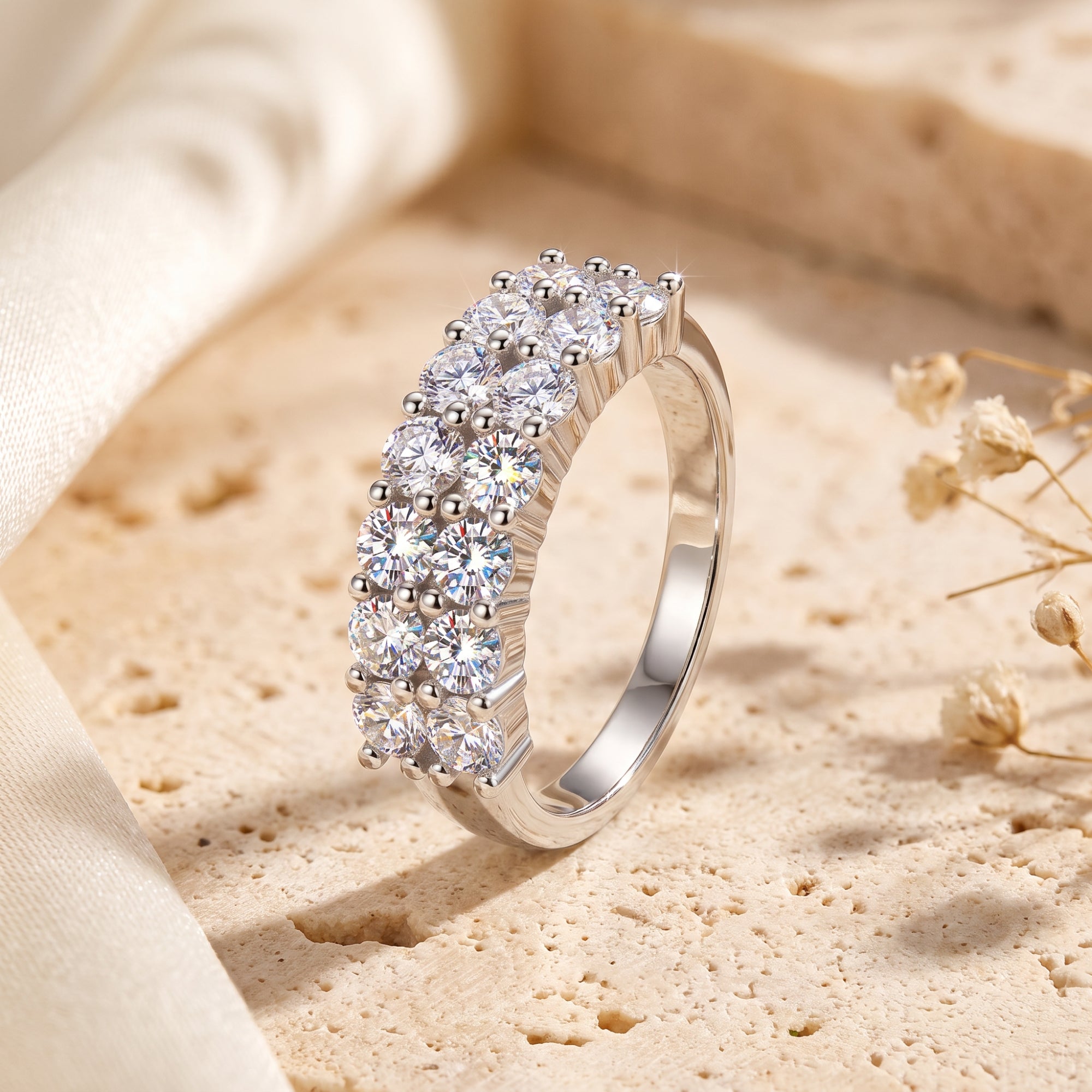 Three-row sterling silver band ring with round cubic zirconia on a stone surface.