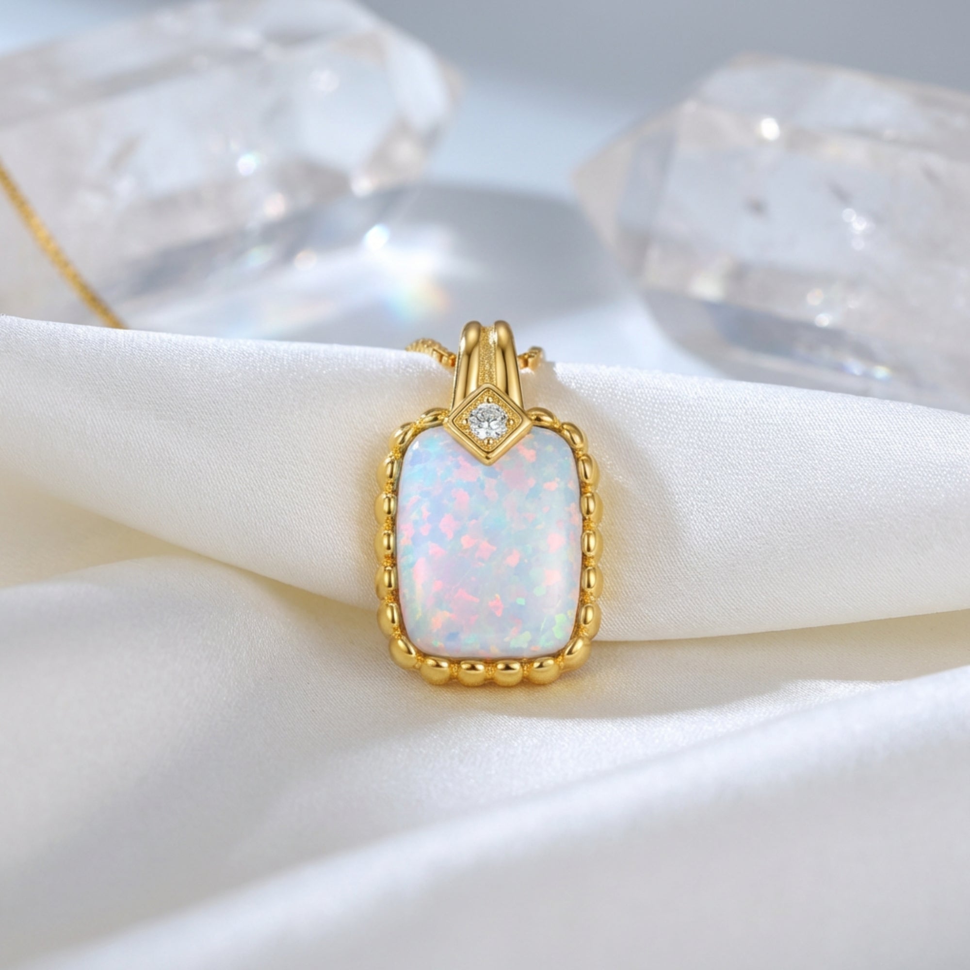 Gold vermeil cushion cut white opal pendant necklace displayed on white silk with crystal accents.