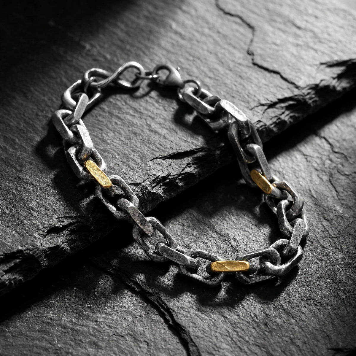Close-up view of the two-tone heavy link chain bracelet with gold-tone accents on textured dark slate.