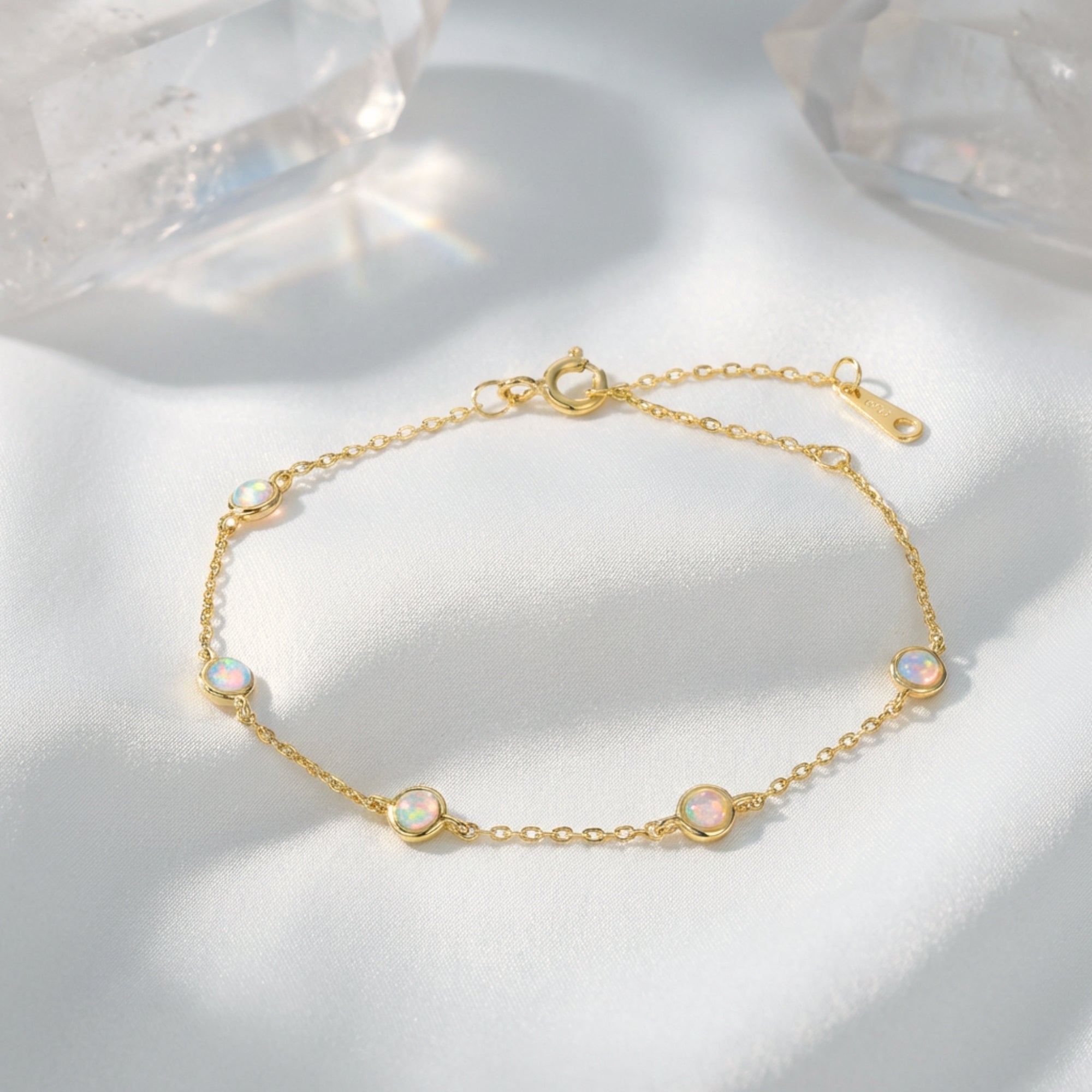 Gold-tone S925 sterling silver station bracelet with five round cut opals on white silk with crystals.