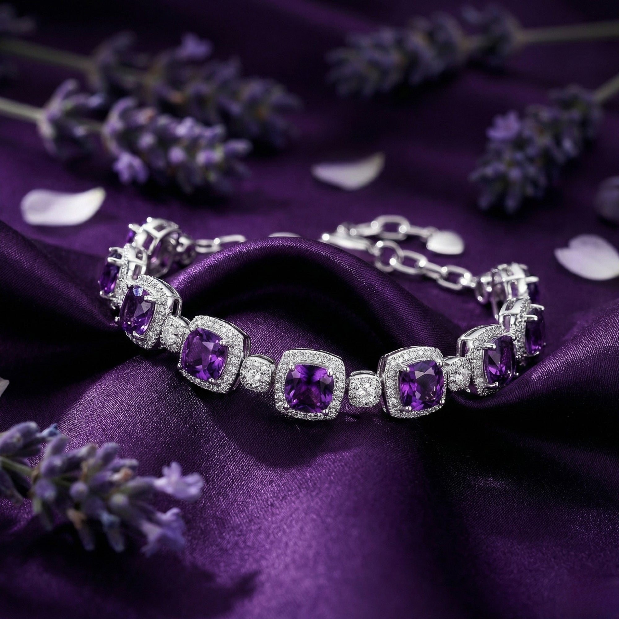 Close-up of cushion cut amethyst stones in a sterling silver bracelet setting on purple fabric.