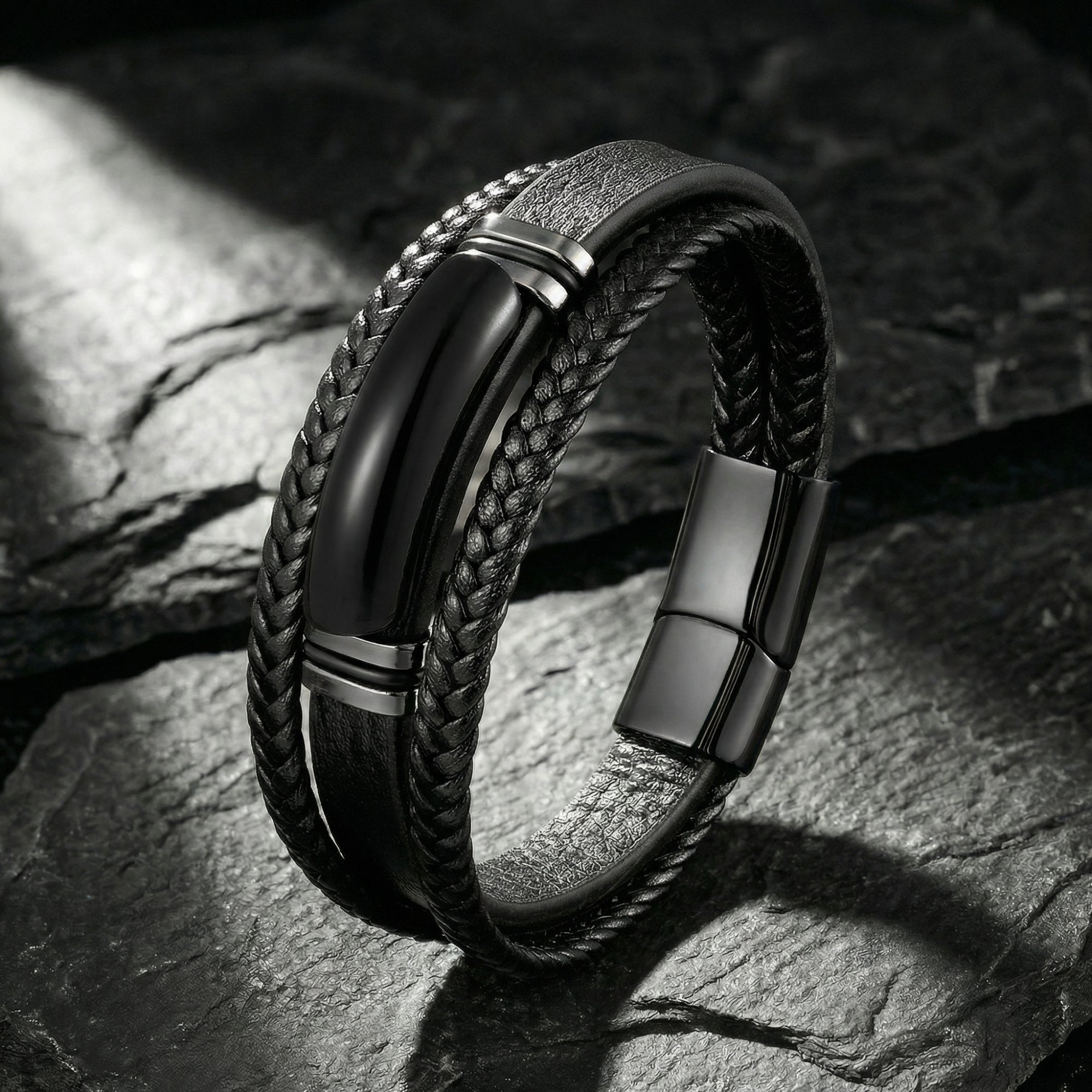 Black braided leather men's bracelet with a black stainless steel magnetic clasp on a dark stone background.