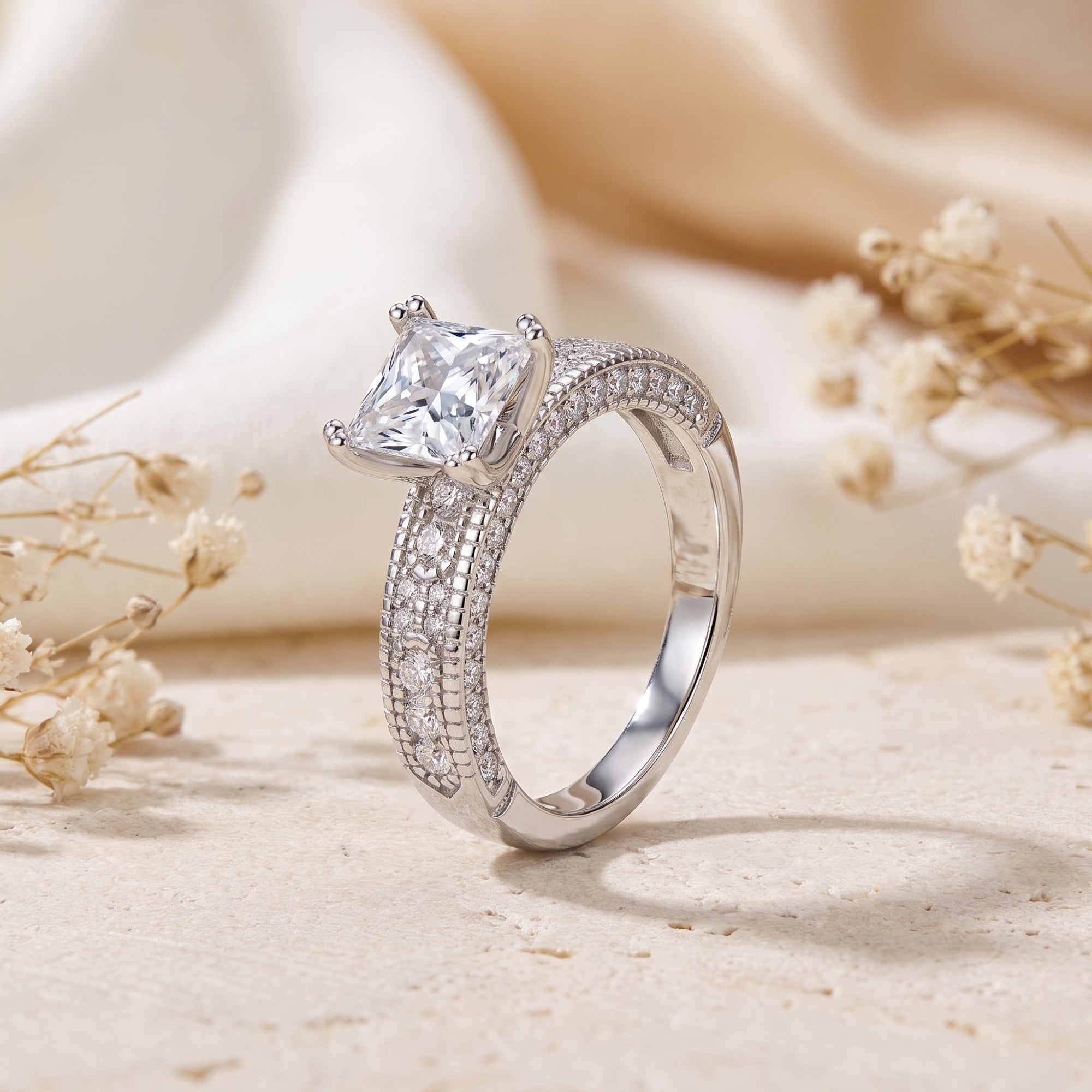 Princess cut CZ ring in S925 silver on stone with floral accents.