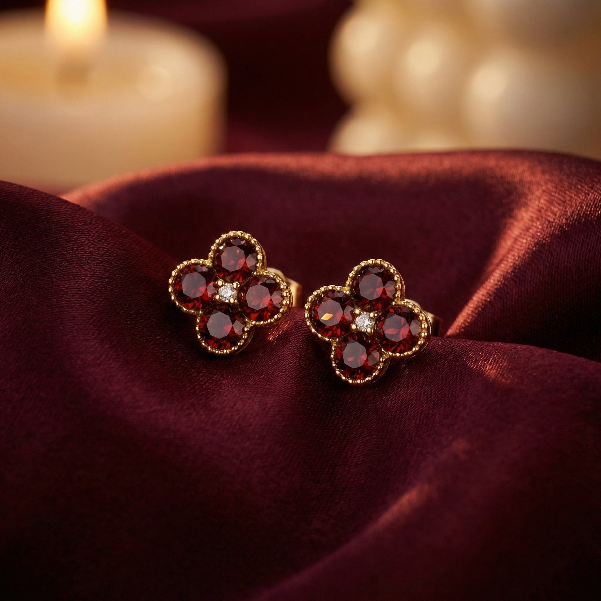 Ambrosia floral stud earrings in 18K yellow gold with round garnets and diamonds on burgundy silk.