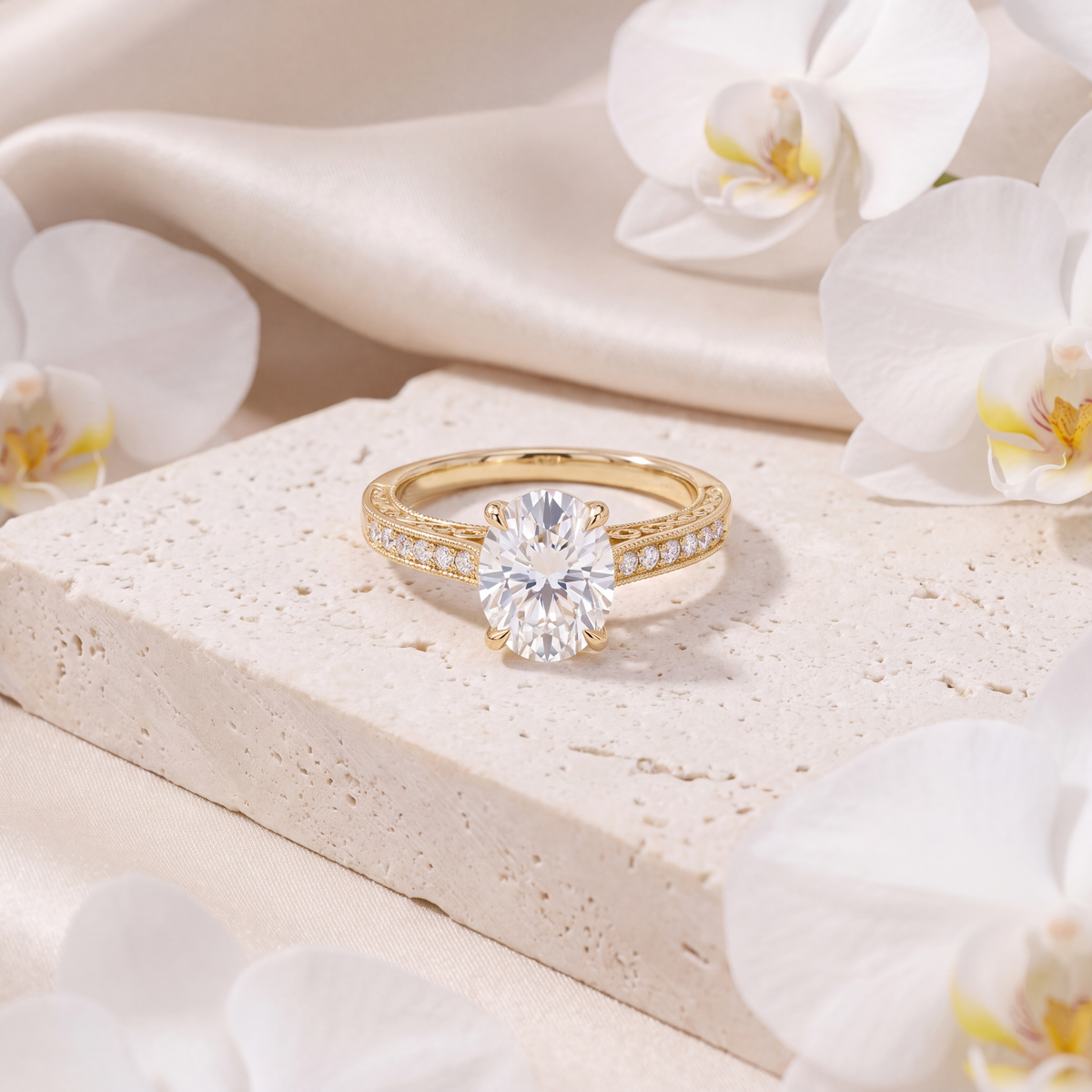Yellow gold oval moissanite engagement ring with a milgrain accent band displayed on a stone surface.
