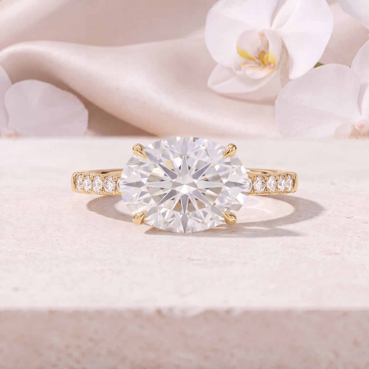 An East-West oval cut moissanite engagement ring featuring a pavé band in yellow gold.
