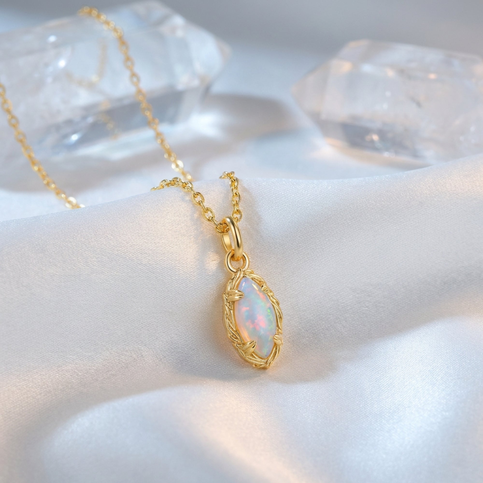 Gold marquise-cut white opal necklace displayed on white silk with crystal accents.