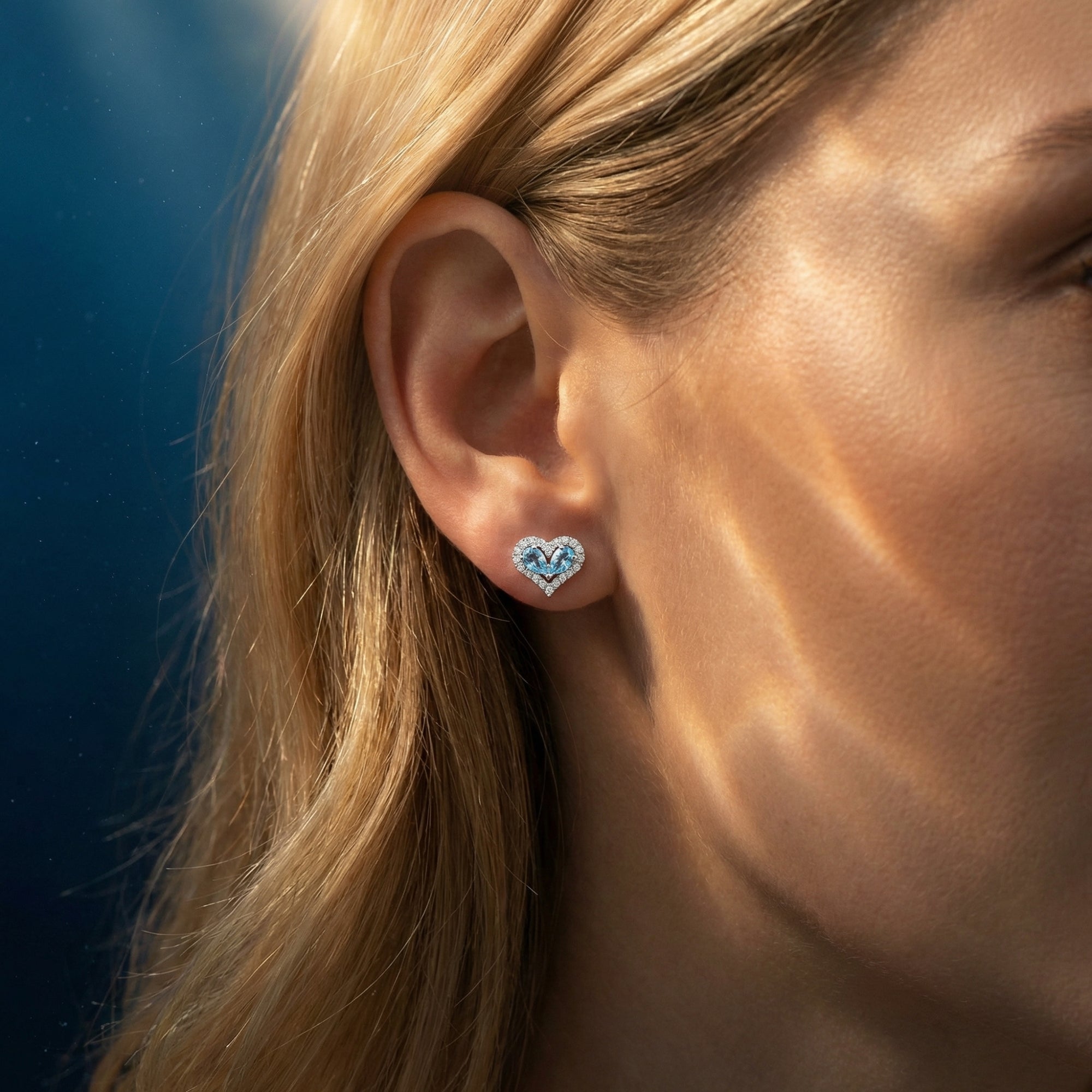 Woman wearing a heart-shaped pear-cut natural aquamarine and diamond halo stud earring in white gold.