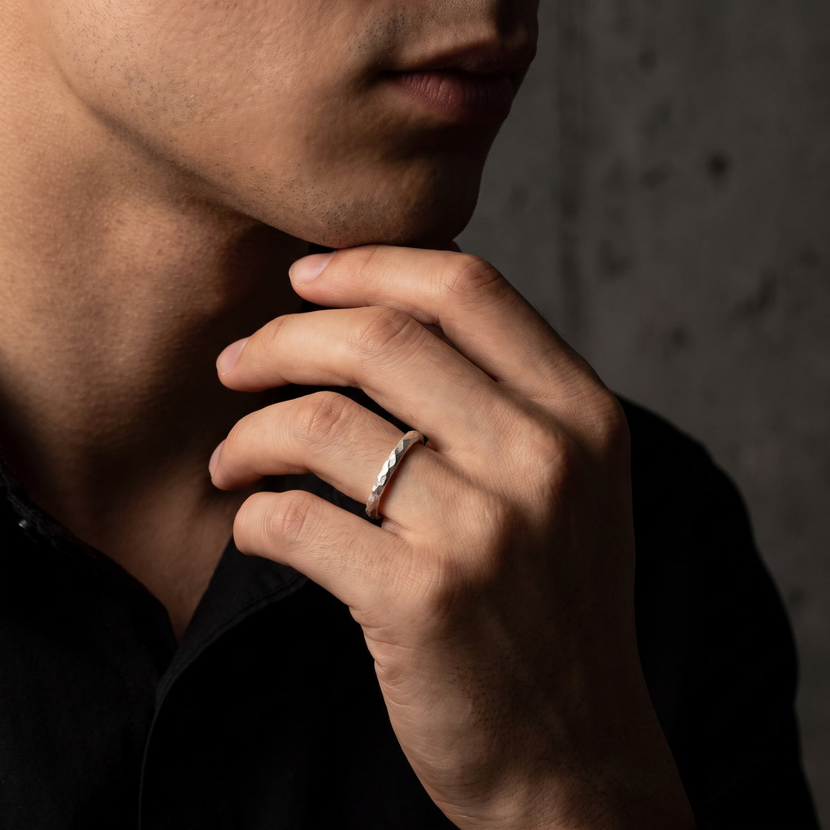 Man resting his chin on his hand while wearing the textured open ring on his ring finger.