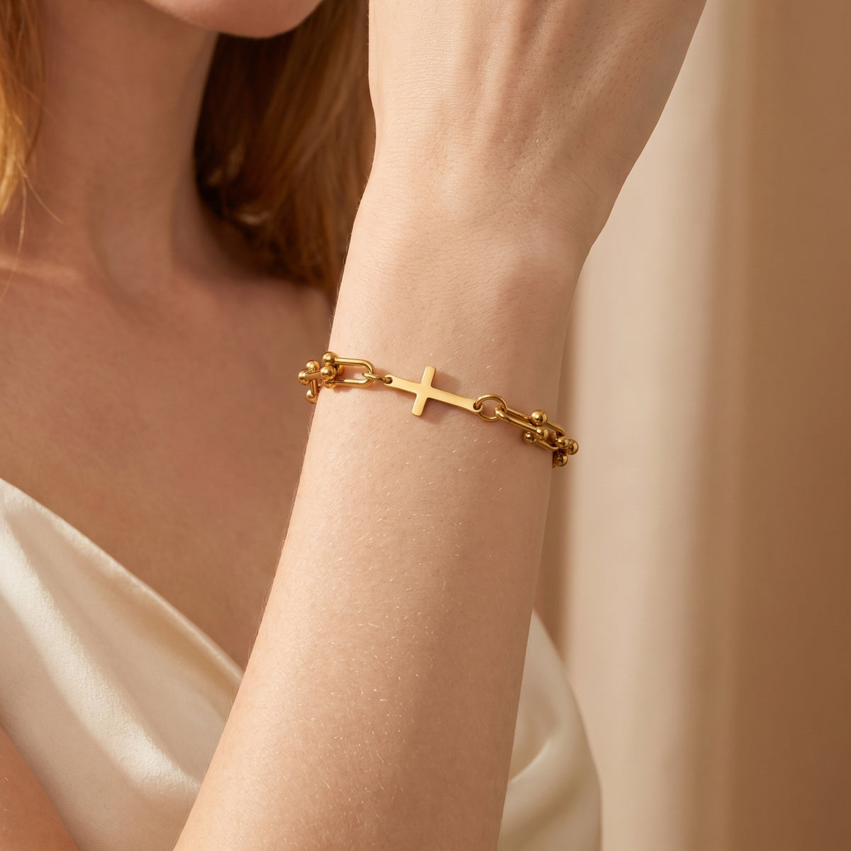 Close-up of a woman wearing the gold-tone horizontal cross U-link bracelet on her wrist.