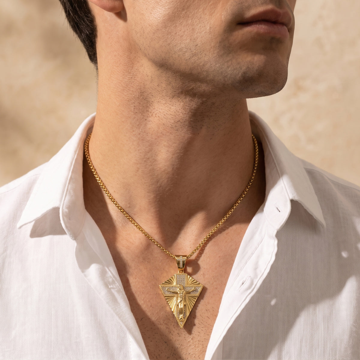 Close-up of a person wearing the gold-finished crucifix necklace over an open white shirt.