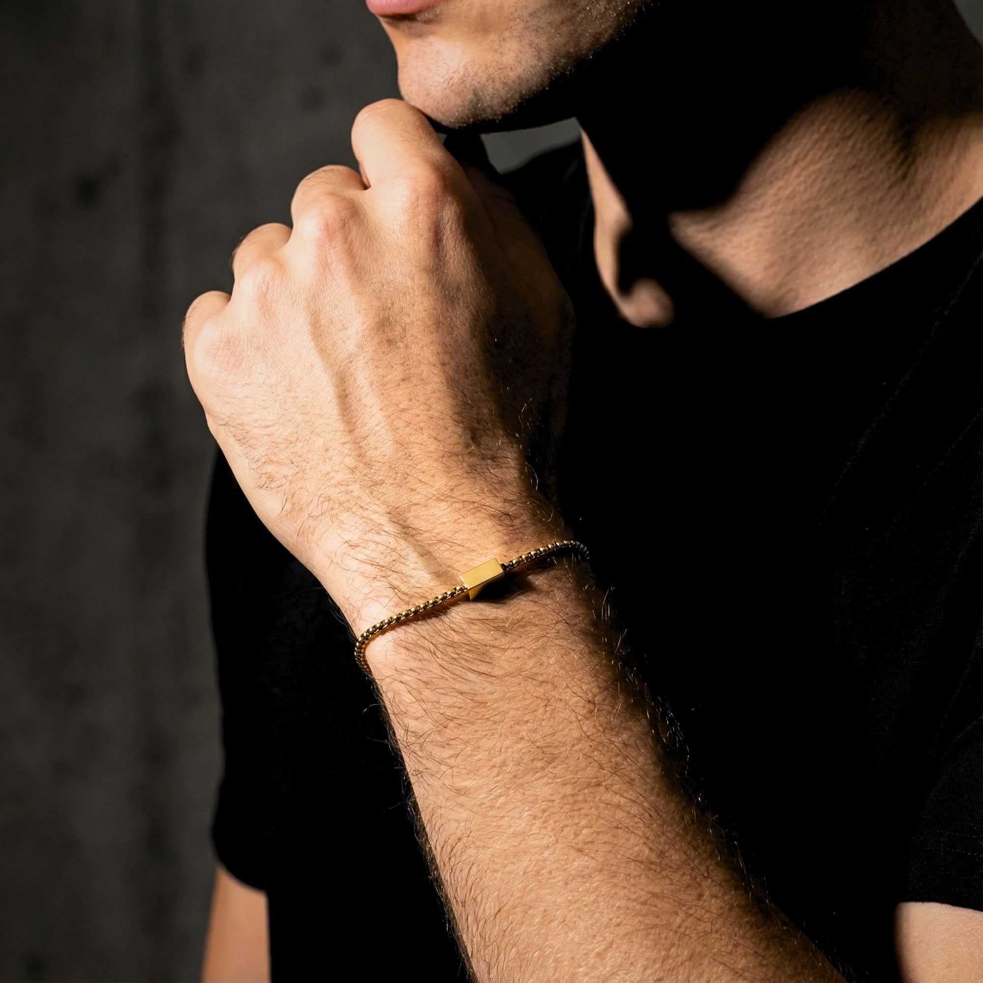 Men's gold stainless steel 5mm Cipher ID bracelet worn on a wrist by a model in a black t-shirt.