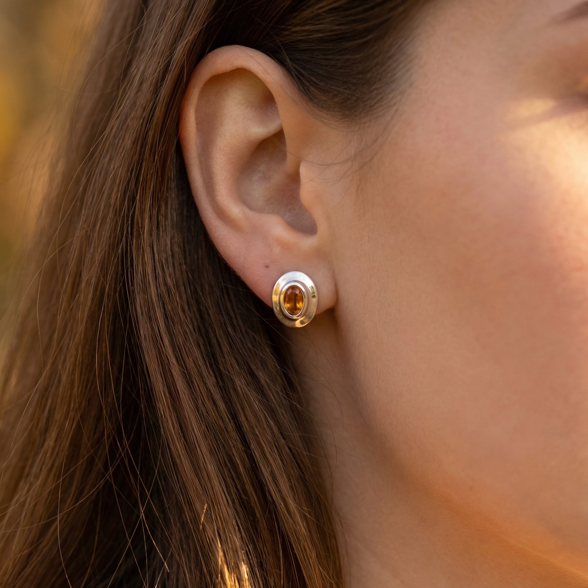 Model wearing a silver oval cut citrine earring, showing how it sits on the earlobe.