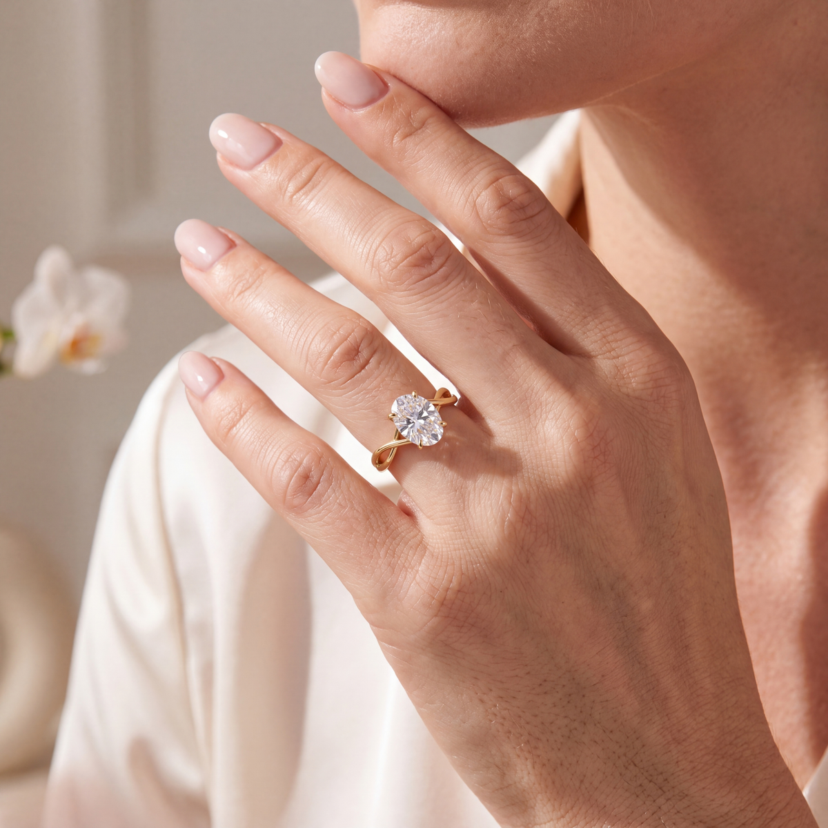 Close-up of a woman wearing an oval moissanite ring with a twisted yellow gold band on her finger.