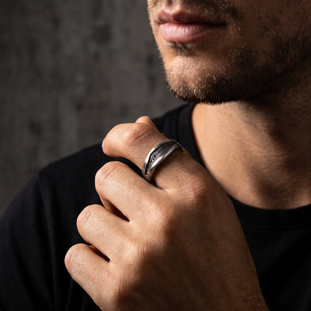 Close-up of a man wearing the silver wood grain open ring on his index finger.