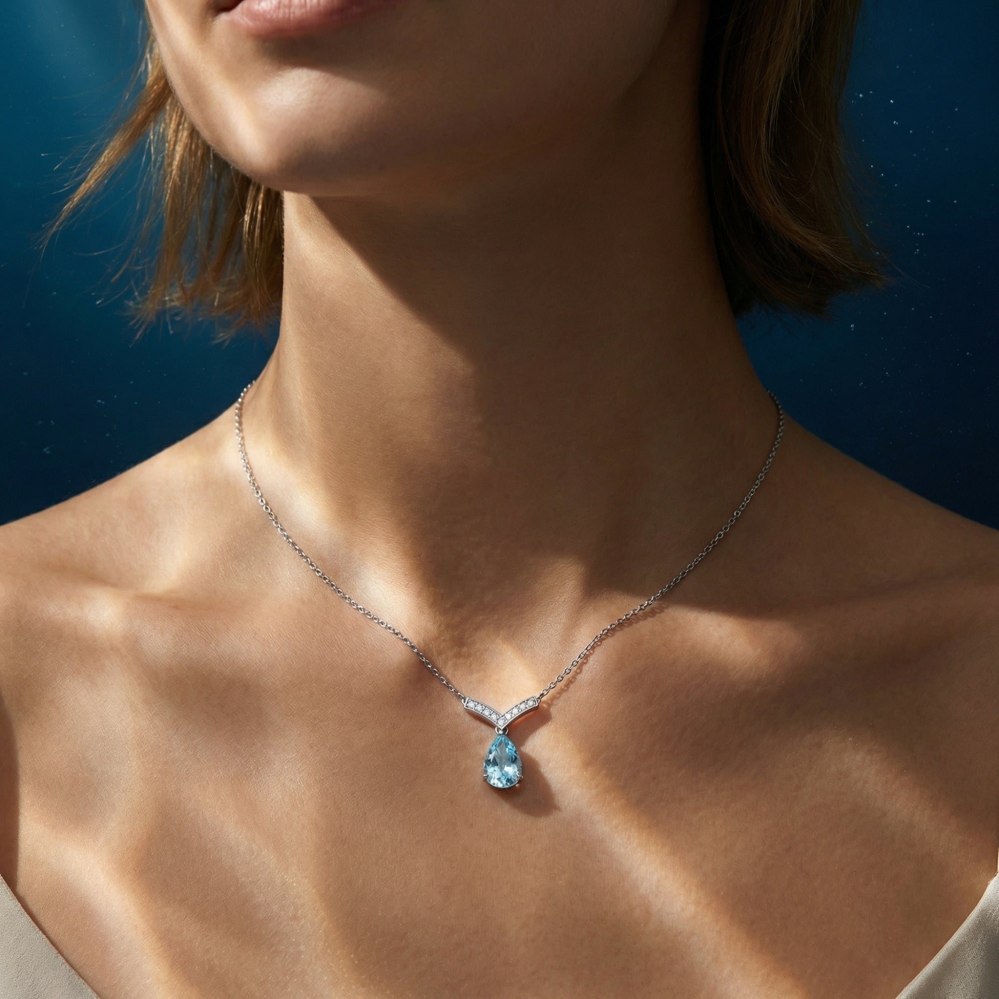 Model wearing the pear cut aquamarine and platinum necklace, showing how the pendant sits on the collarbone.