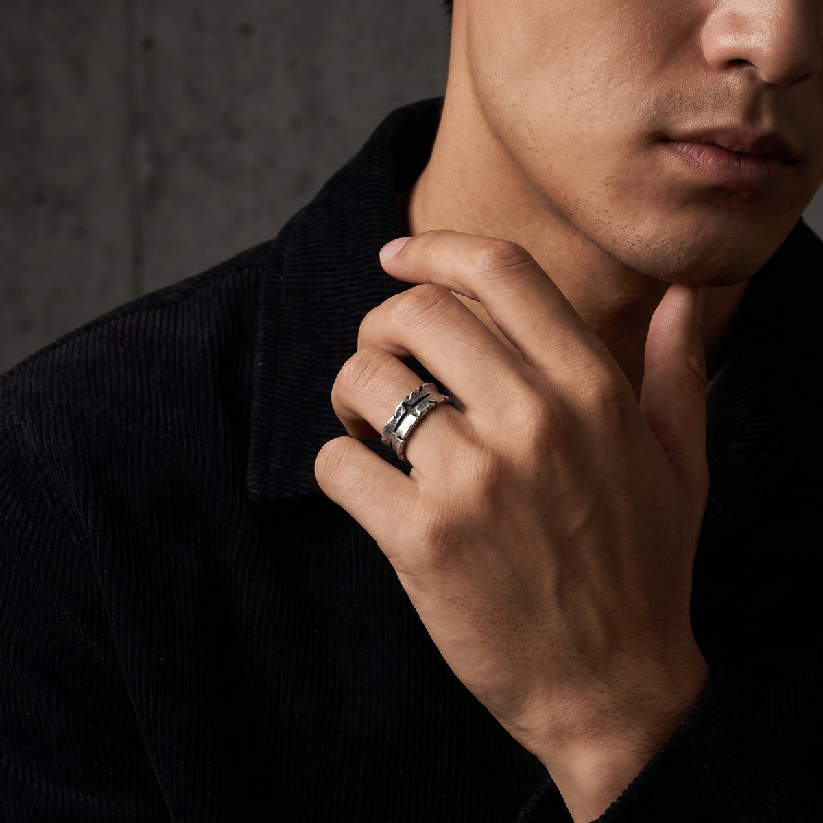 Man wearing the textured silver cross ring while resting his hand beneath his chin.