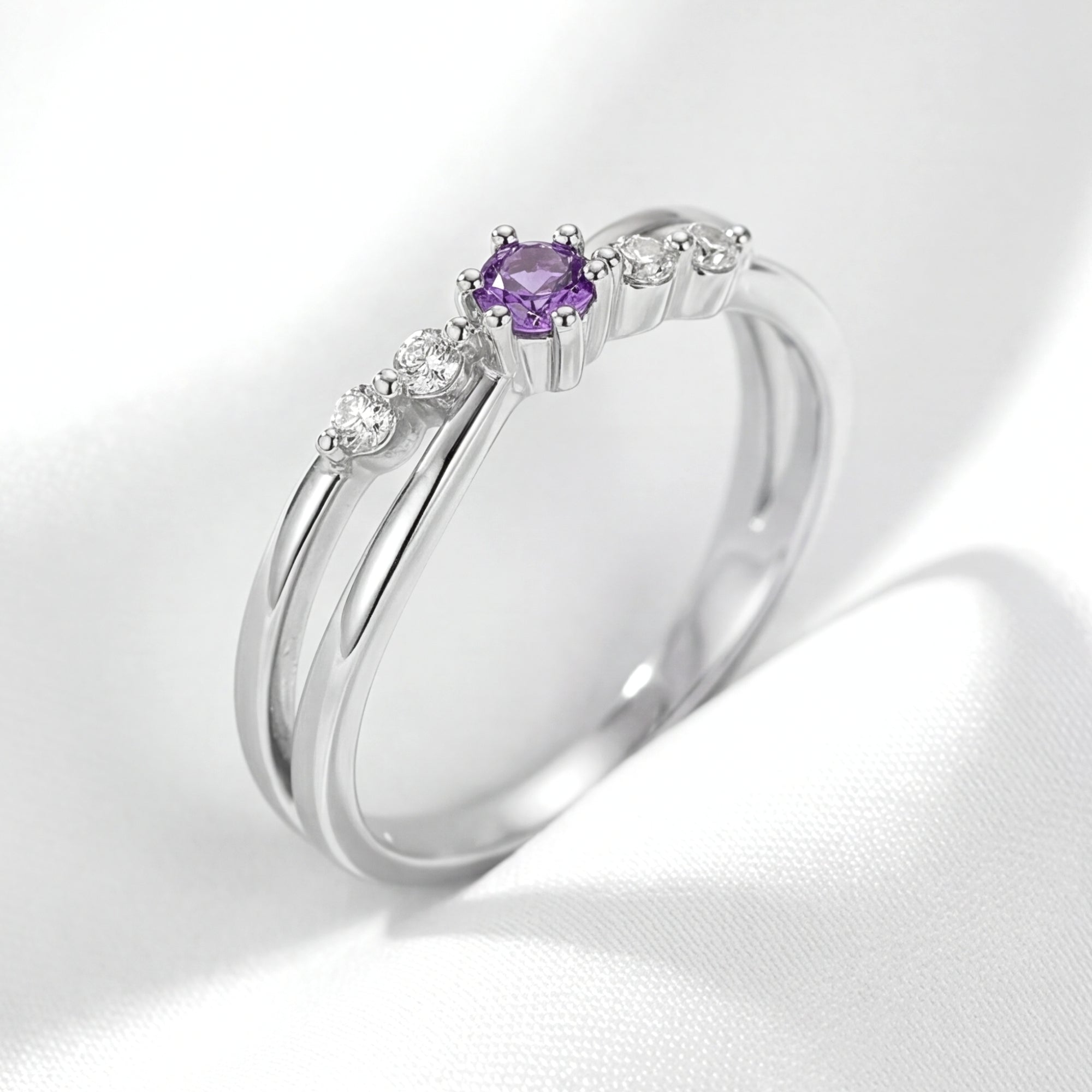 Angled side view of the Astraea sterling silver ring with a round purple amethyst on white fabric.