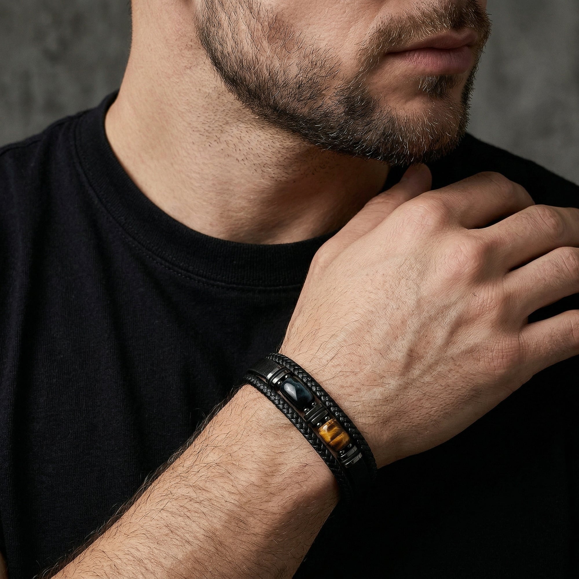 Close-up of a man's wrist wearing the black braided leather Citadel bracelet with a tiger's eye stone.