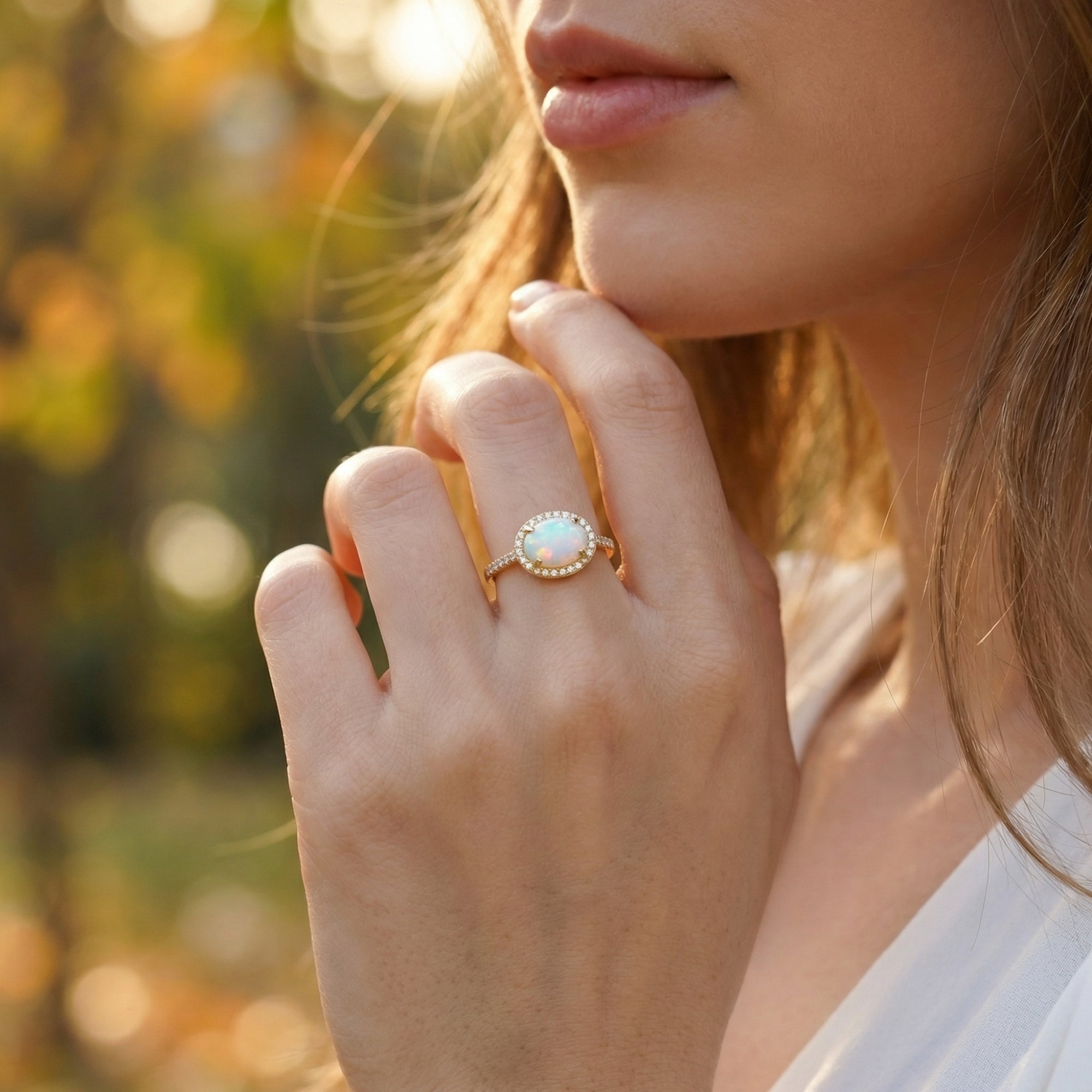 Model wearing the gold vermeil Magnolia statement ring with an oval cut natural opal in an outdoor setting.
