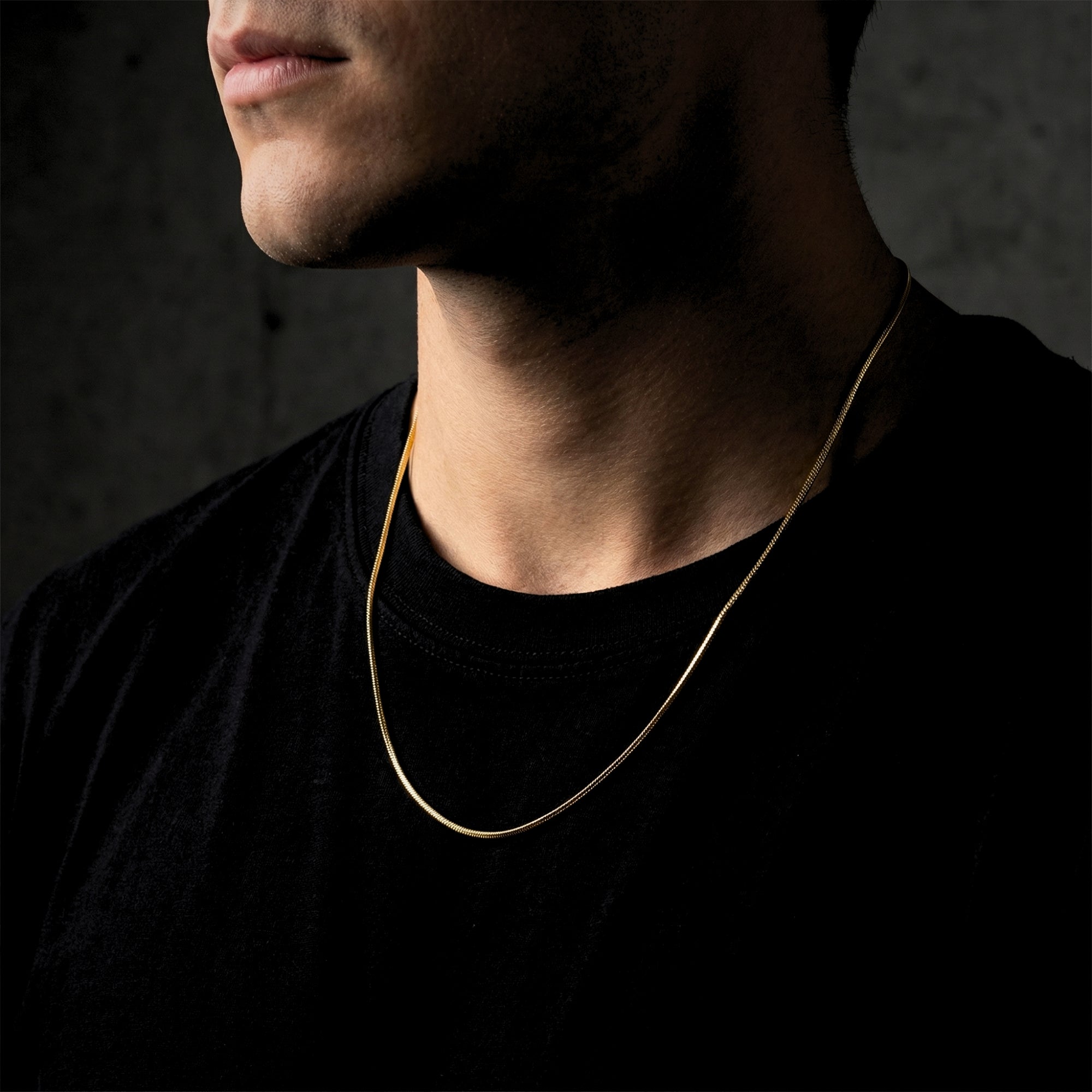 Gold stainless steel Square Dance Chain worn by a man over a black t-shirt.