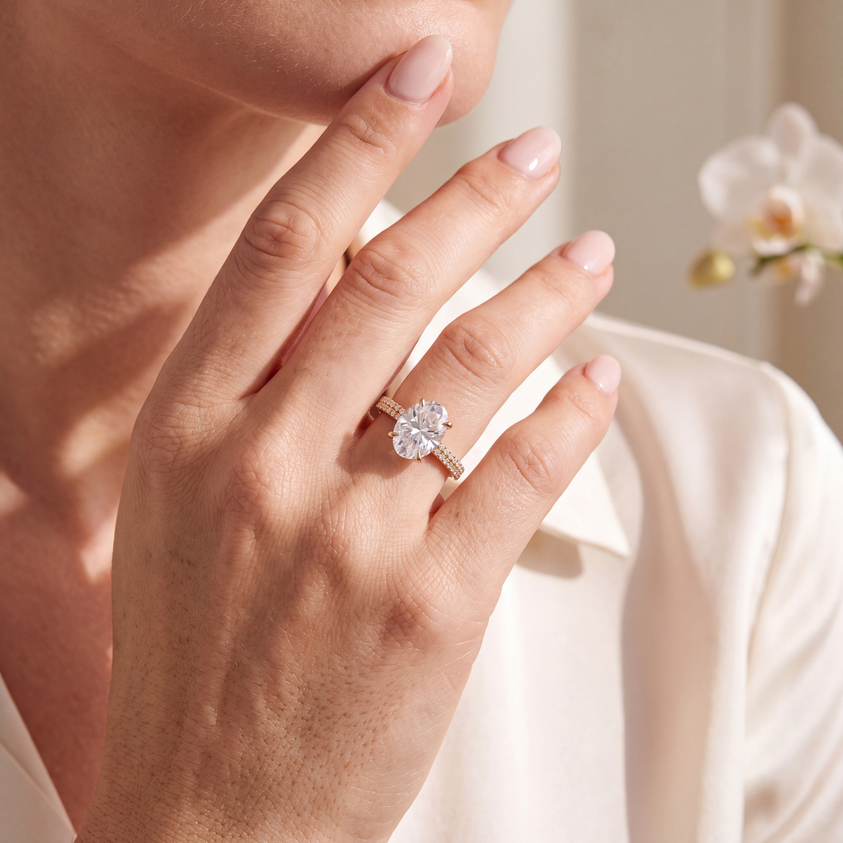 Woman wearing a gold oval moissanite engagement ring with a double-row pave band.
