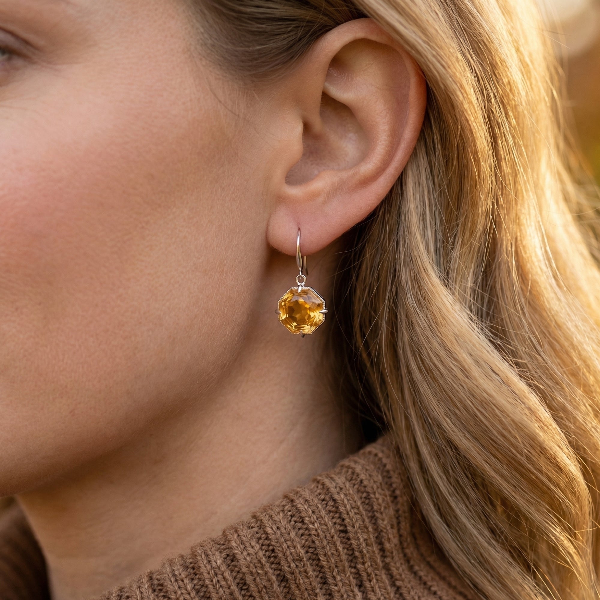 Woman wearing a Cyra octagon-cut citrine drop earring in silver, showcasing the 31mm drop length.