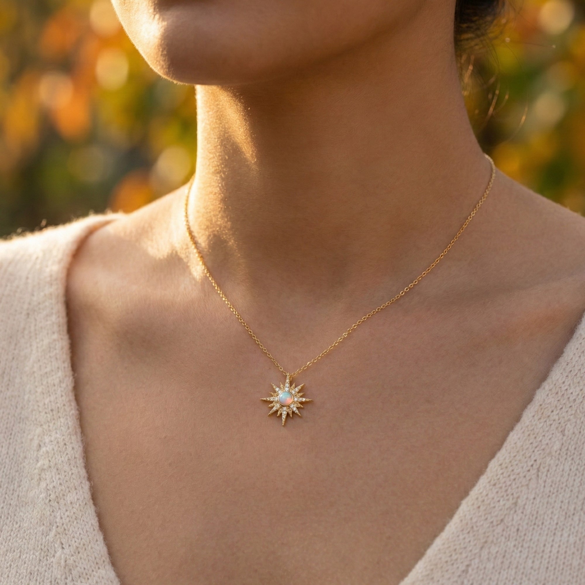 Model wearing the gold Astralia starburst necklace with a round white opal pendant in natural light.
