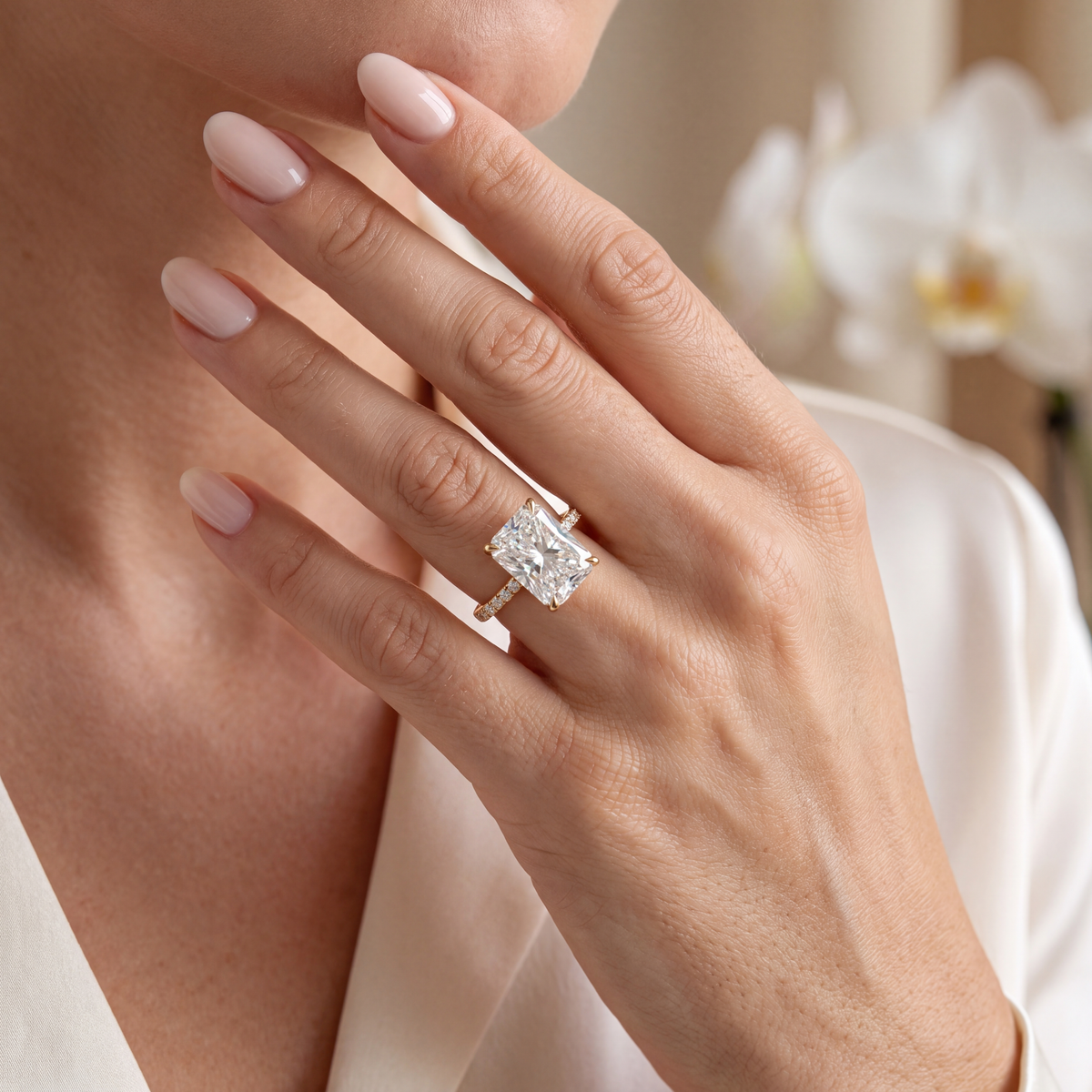A model wearing a radiant cut moissanite engagement ring with a yellow gold pavé band.