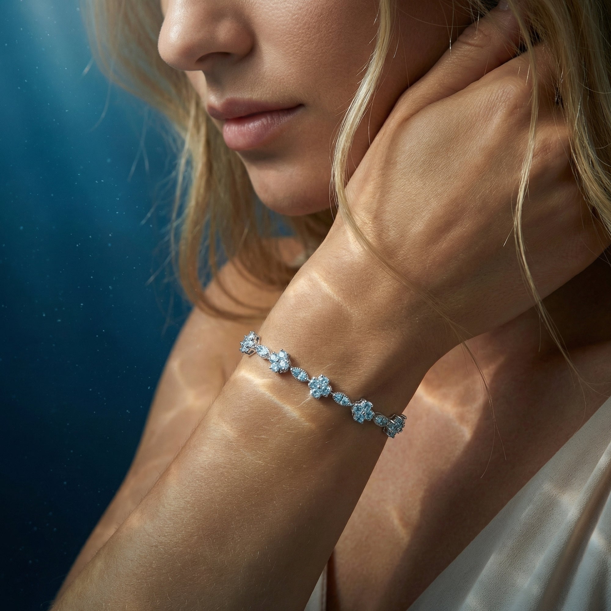 Woman wearing the Aquarina aquamarine station bracelet in silver on her wrist with soft lighting.