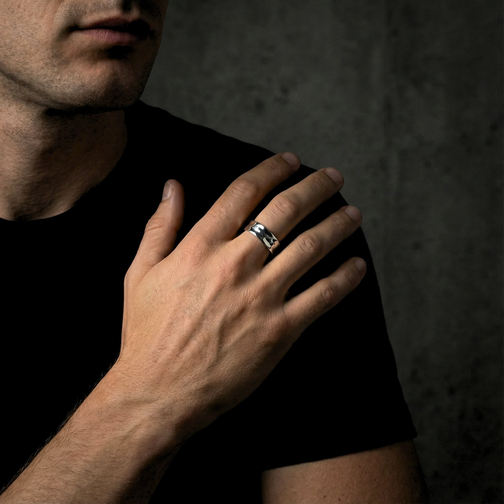 Silver stainless steel Origin Flex adjustable ring worn on a man's ring finger.