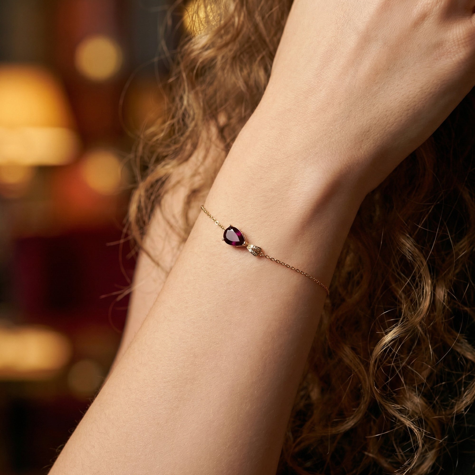 Maelle pear cut garnet bracelet in 18K rose gold worn on a woman's wrist.