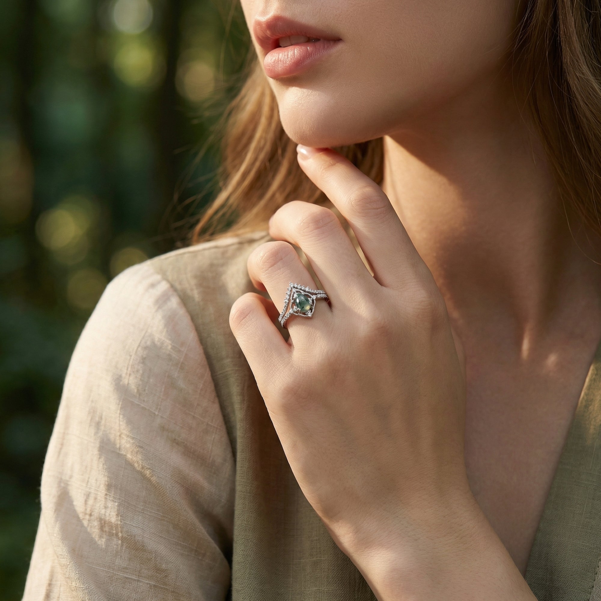 Model wearing the oval cut natural moss agate ring set in sterling silver against a soft outdoor background.
