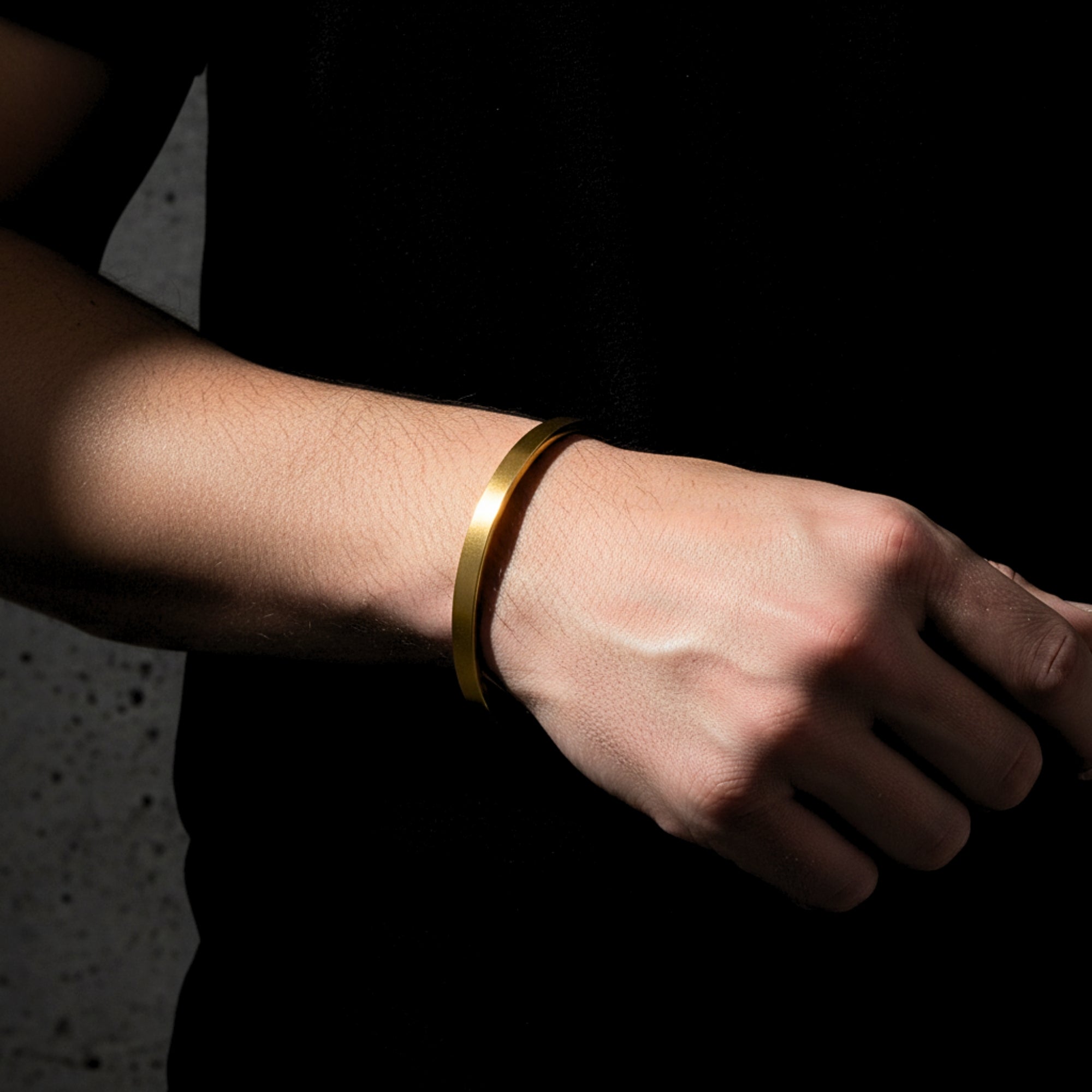 Men's gold stainless steel Meridian Cuff bracelet worn on a wrist against a dark background.