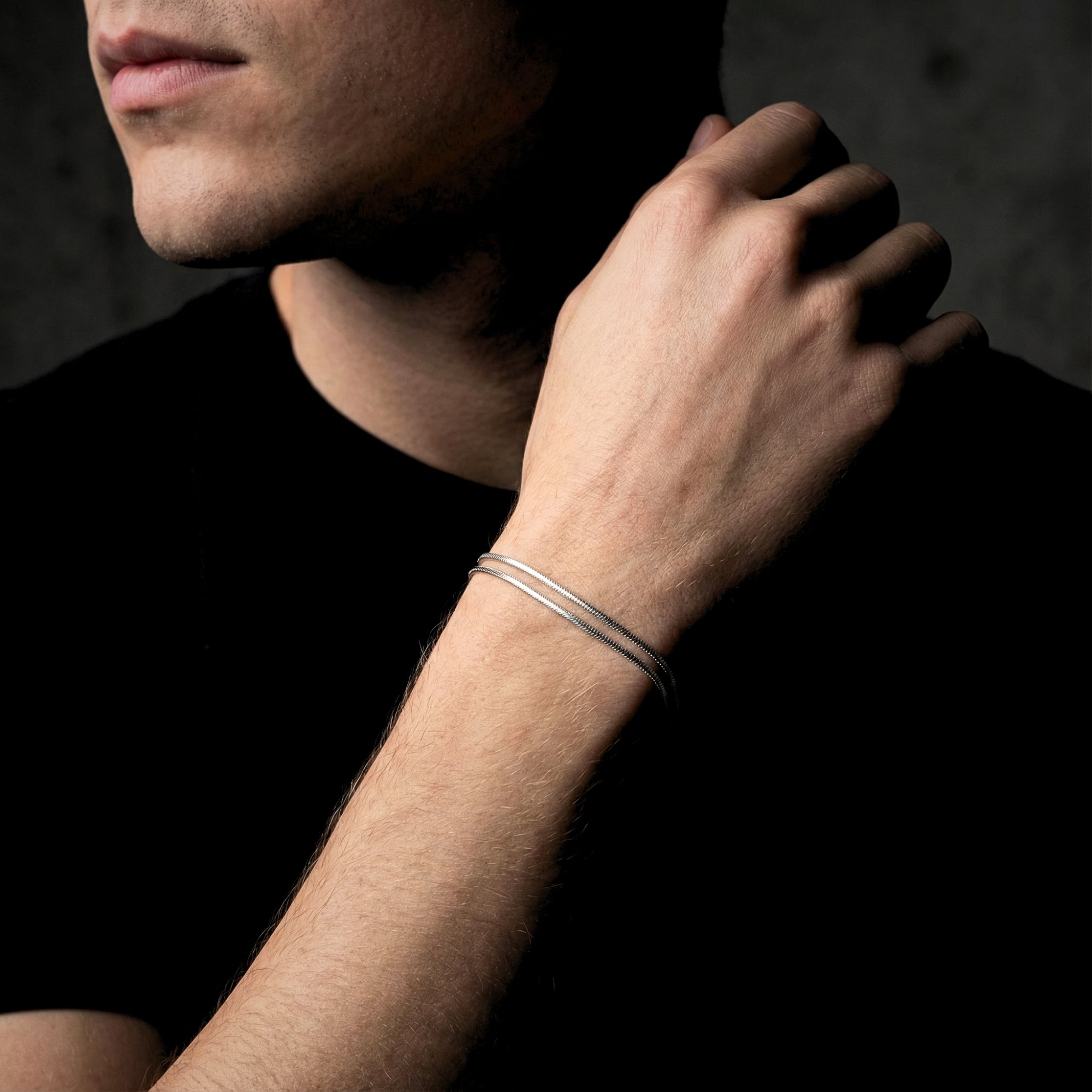 Men's silver stainless steel square link bracelet worn on a wrist, styled with a black t-shirt.