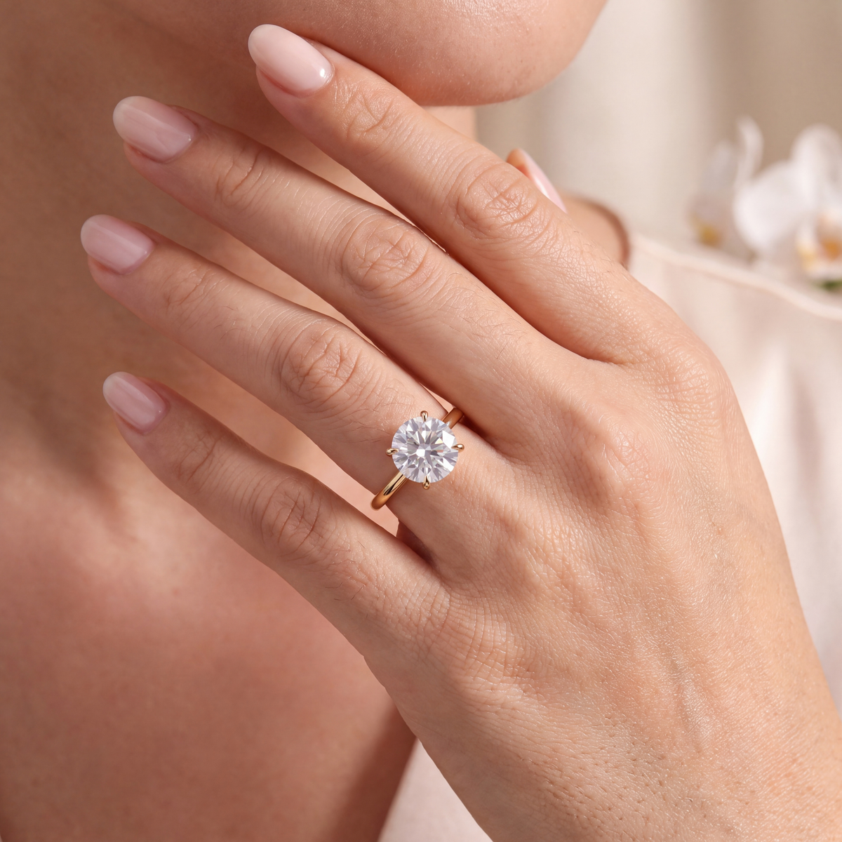Yellow gold round cut moissanite solitaire ring worn on a woman's finger.