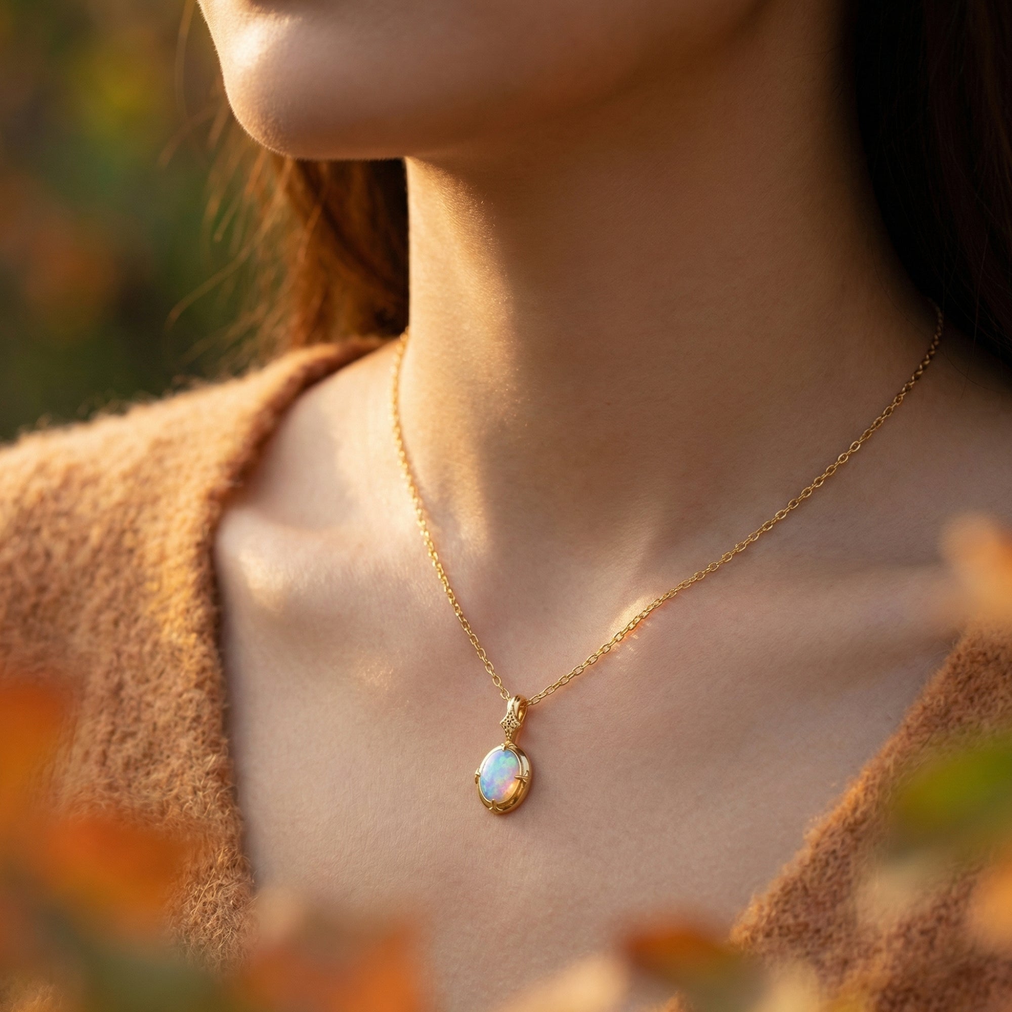 Woman wearing the gold-tone oval white opal pendant necklace in natural outdoor light.