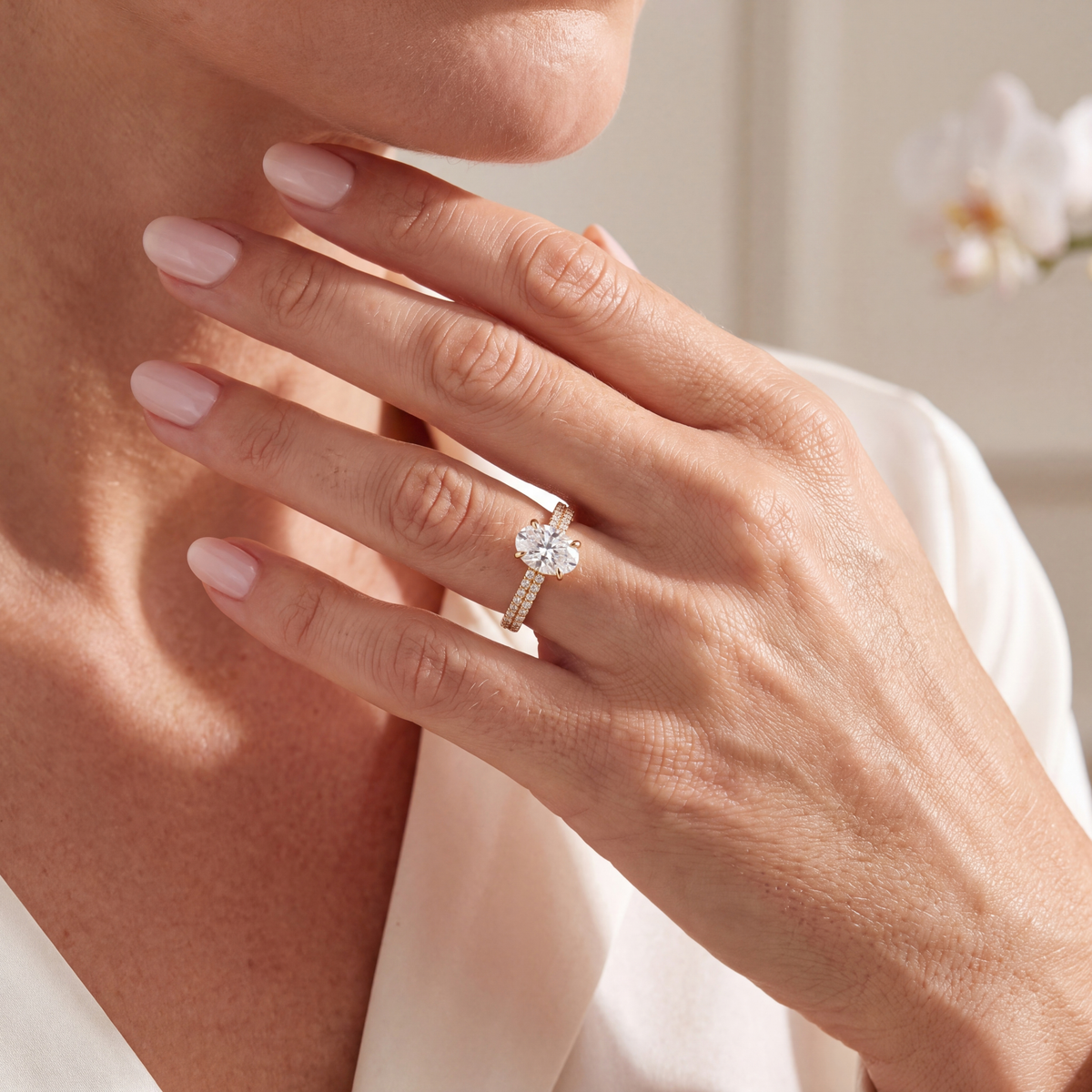 Model wearing a gold oval moissanite engagement ring with double-row pavé band.