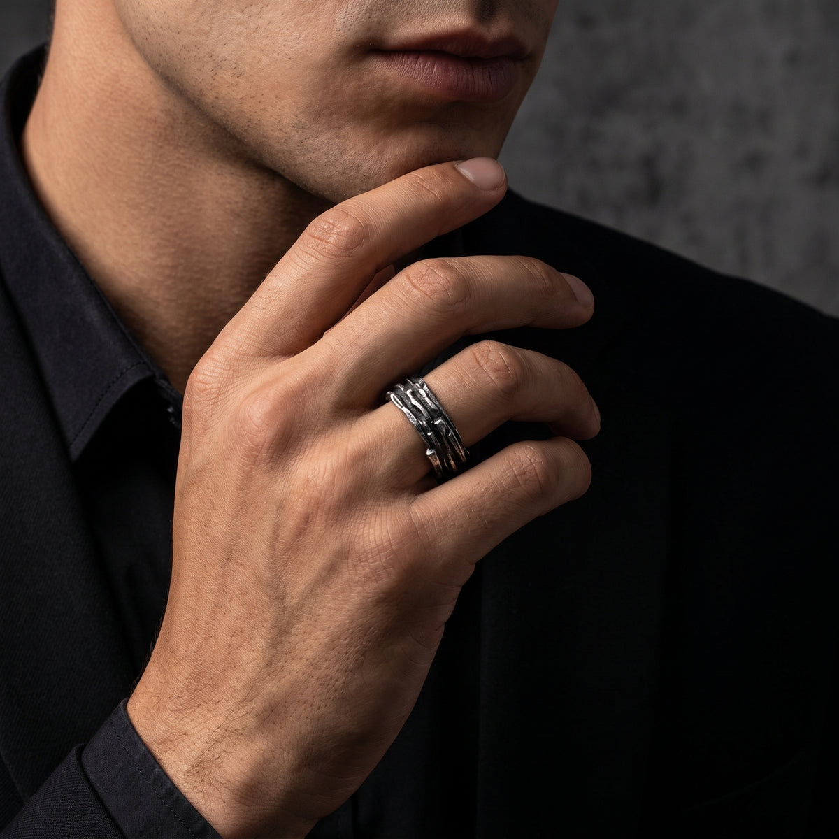 Man wearing the textured oxidized silver open band ring while resting his hand beneath his chin.