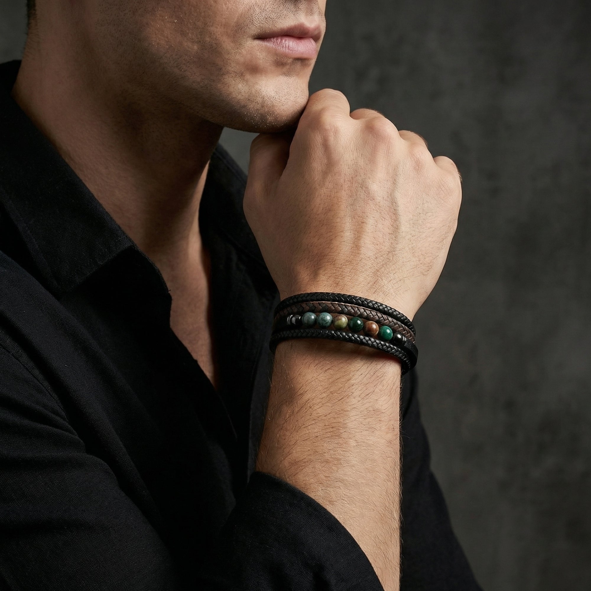Men's black braided leather bracelet with round natural stone beads worn on a wrist.