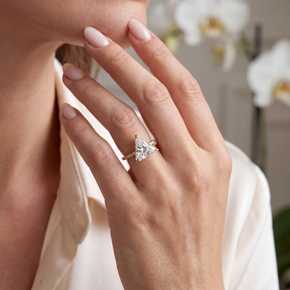 Trillion-cut yellow gold moissanite engagement ring worn on a hand.