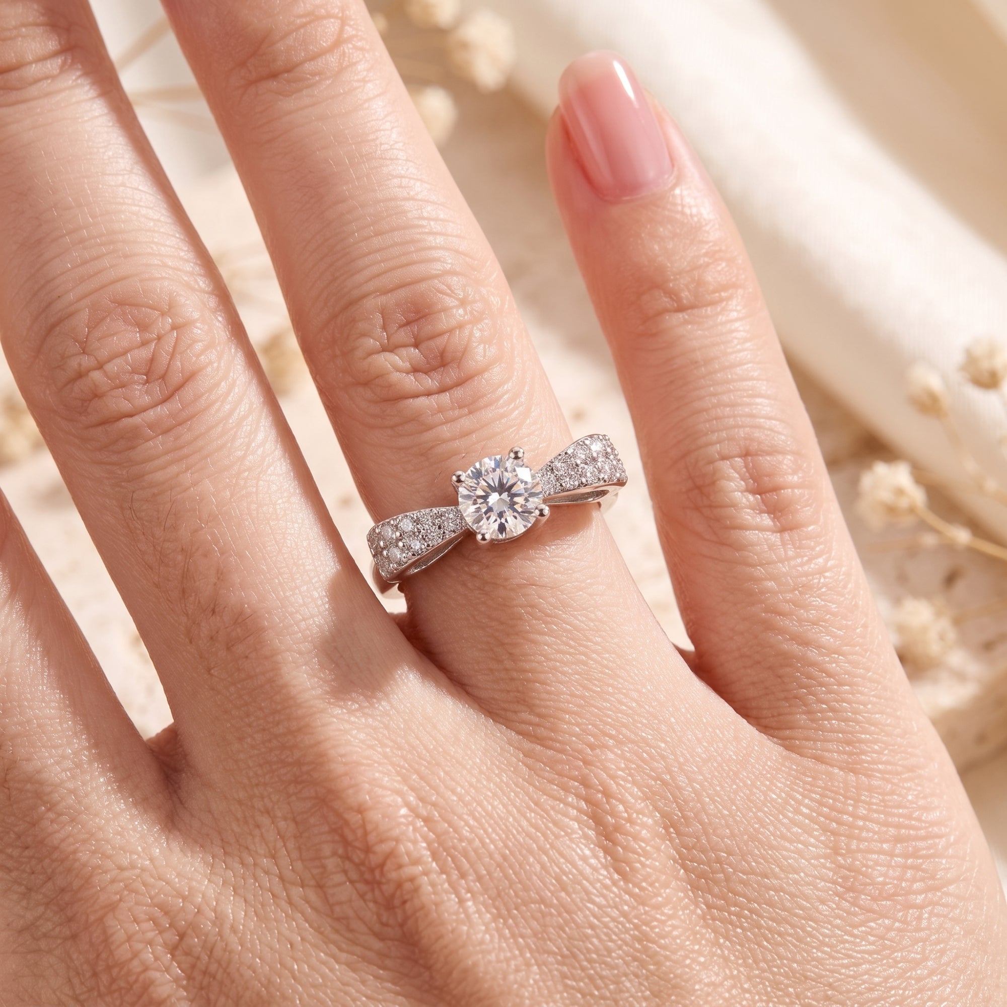 Top view of the sterling silver Juliet bow ring with a round cubic zirconia worn on a finger.